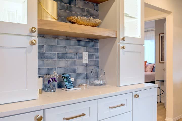 White kitchen counter with gray tile backsplash, cabinets, and a small decorative shelf niche