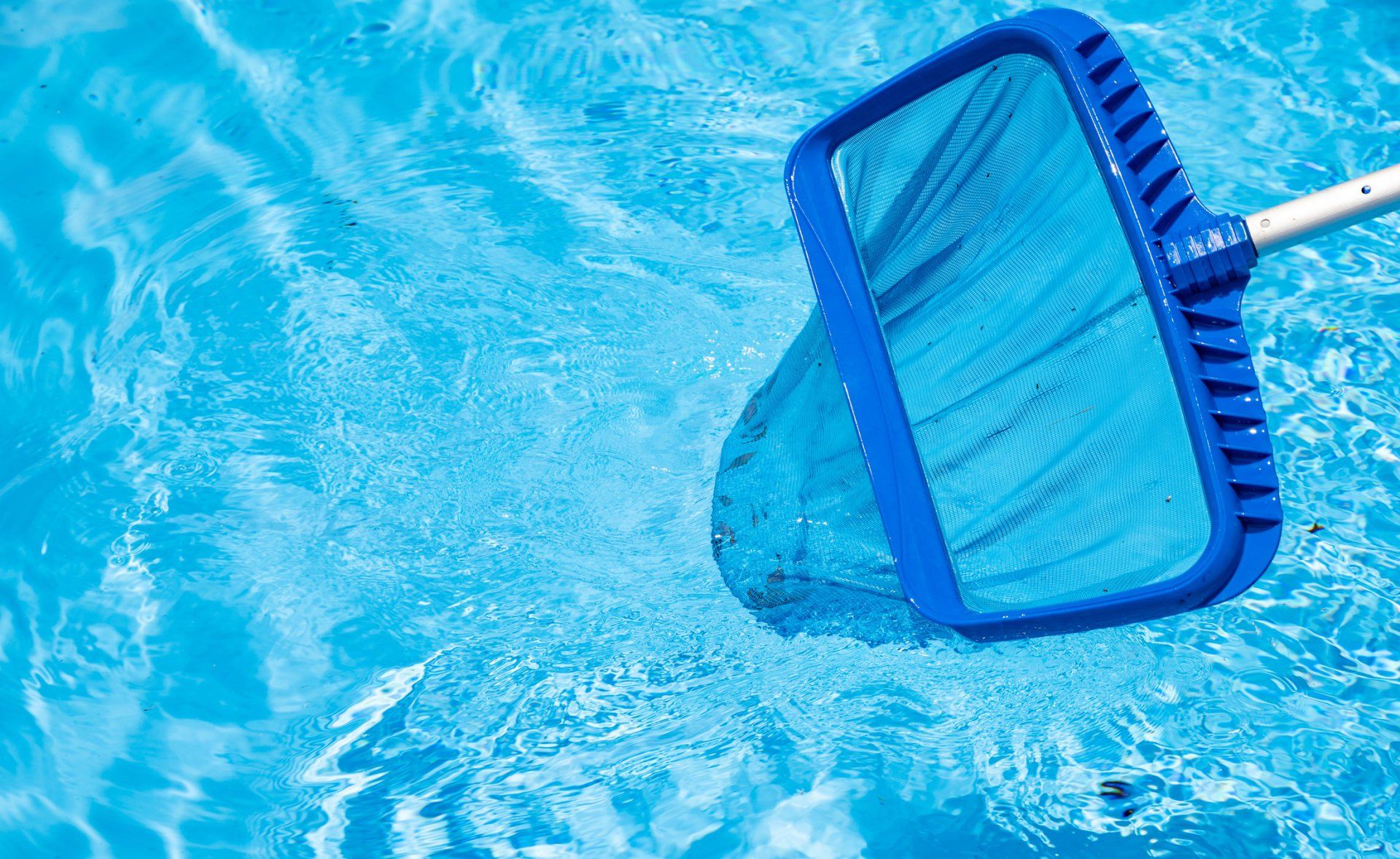 Pool — Muncie, IN — Oxley Softwater Co. Blue pool net skimming the surface of a clear, blue swimming pool.