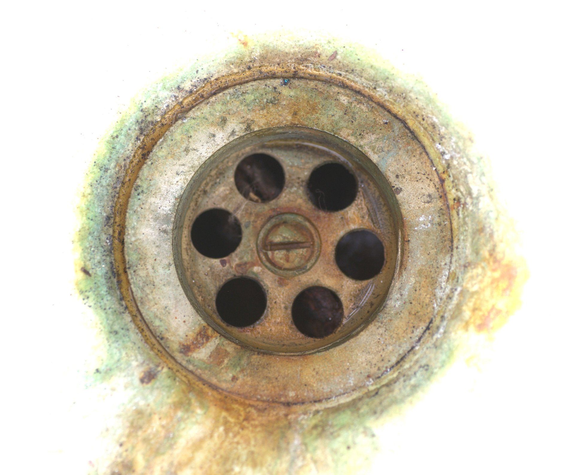 Blue-Green Staining — Muncie, IN — Oxley Softwater Co. Close-up of a dirty, corroded sink drain with circular holes and a central screw, surrounded by grime.