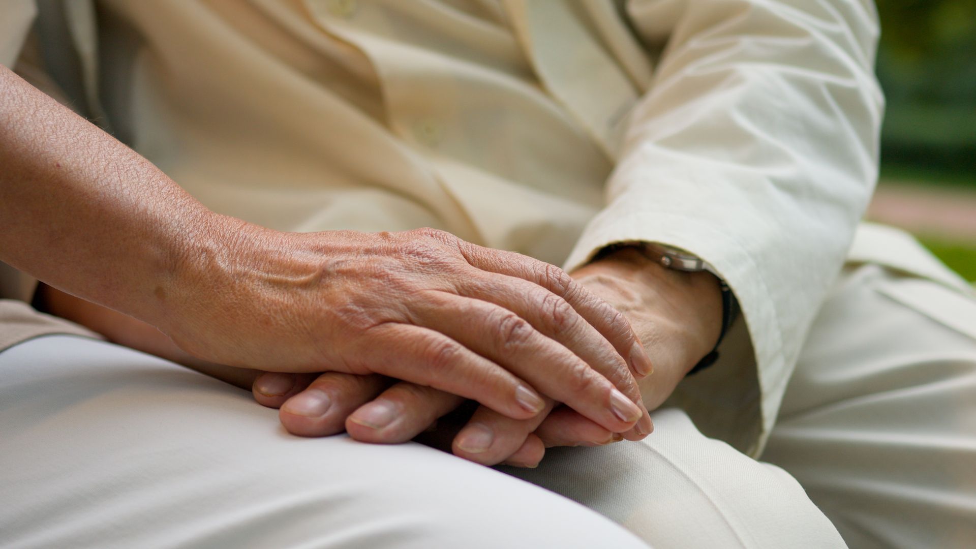 Two hands resting gently on a lap, suggesting comfort or support