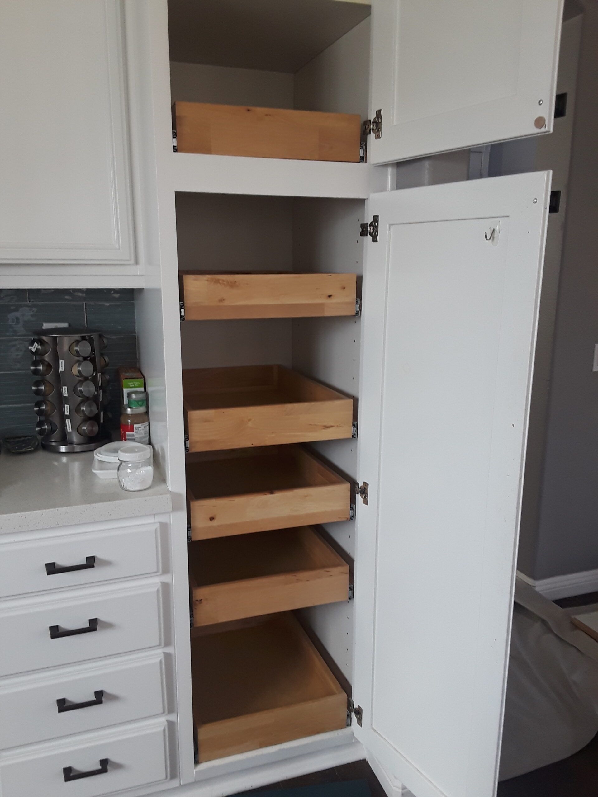 A white cabinet with wooden drawers in a kitchen