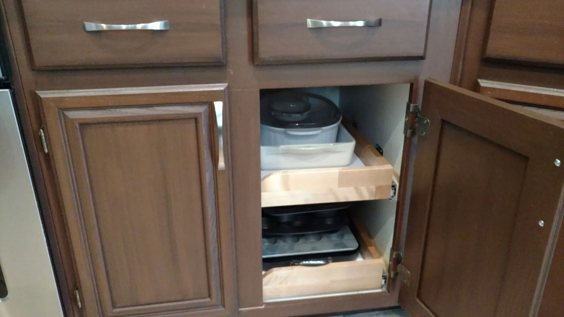 A kitchen cabinet with drawers and a shelf with pots and pans in it.