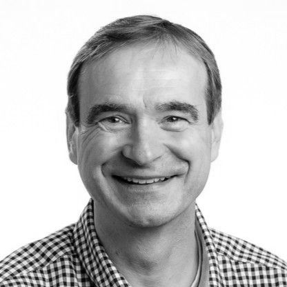 Smiling man in a black-and-white portrait, wearing a checkered shirt.