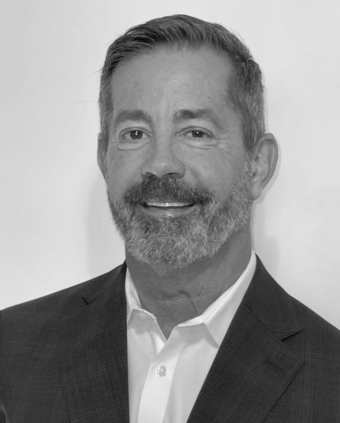 Portrait of a smiling man in a suit and white shirt against a plain background