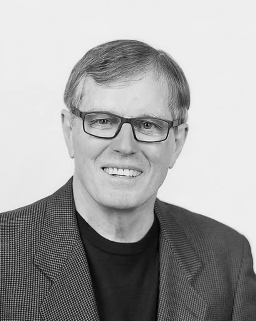 Smiling man in glasses and blazer on a plain light background