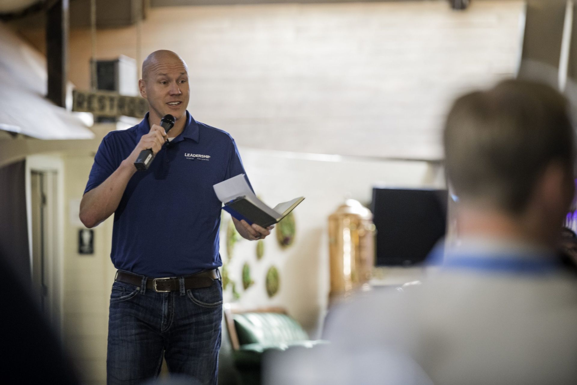 A man is speaking into a microphone while holding a bible.