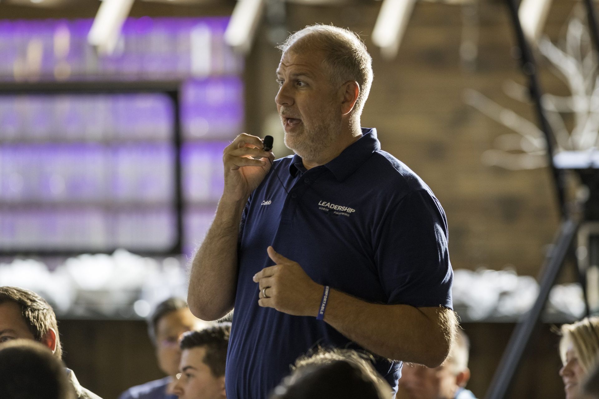 A man in a blue shirt is talking to a group of people.