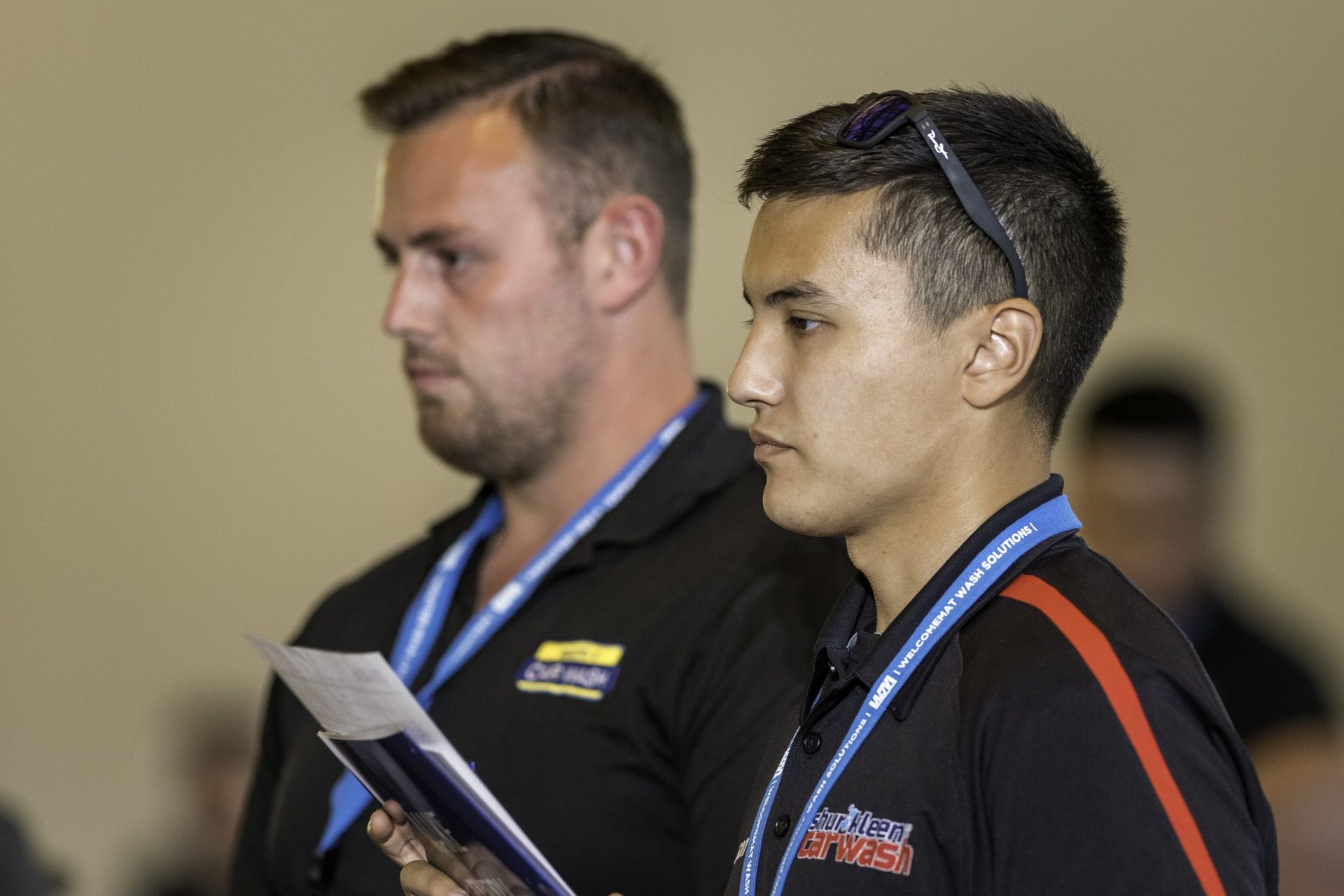 Two men are standing next to each other and one has a lanyard around his neck that says ' safety first '