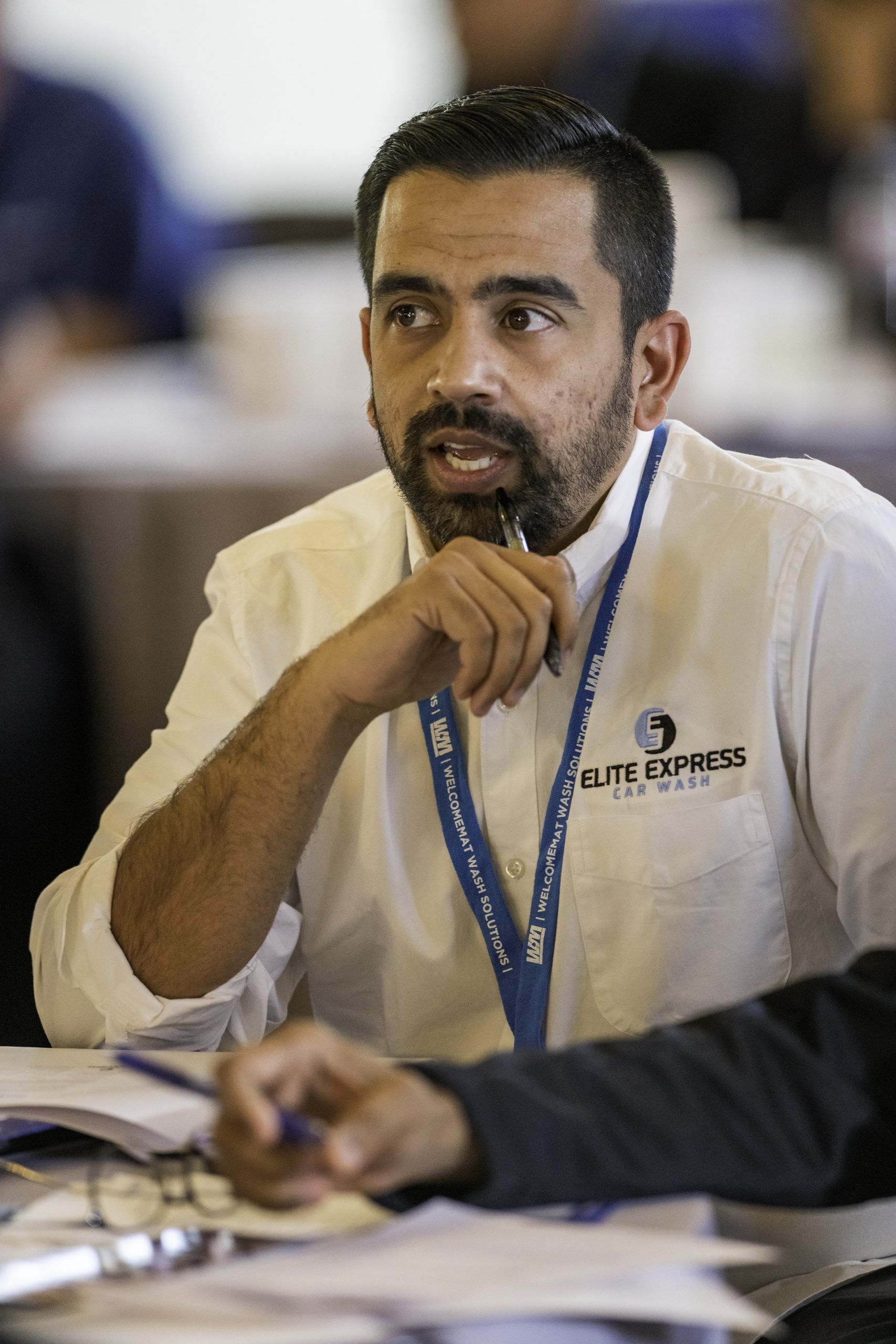 A man with a beard is sitting at a table with a pen in his hand.