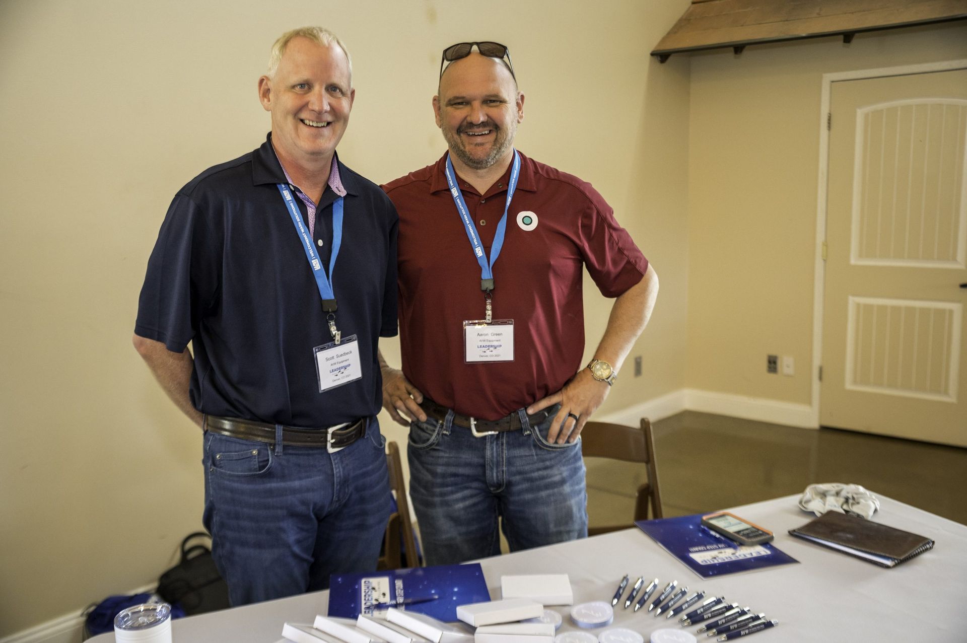 Two men are standing next to each other in front of a table.