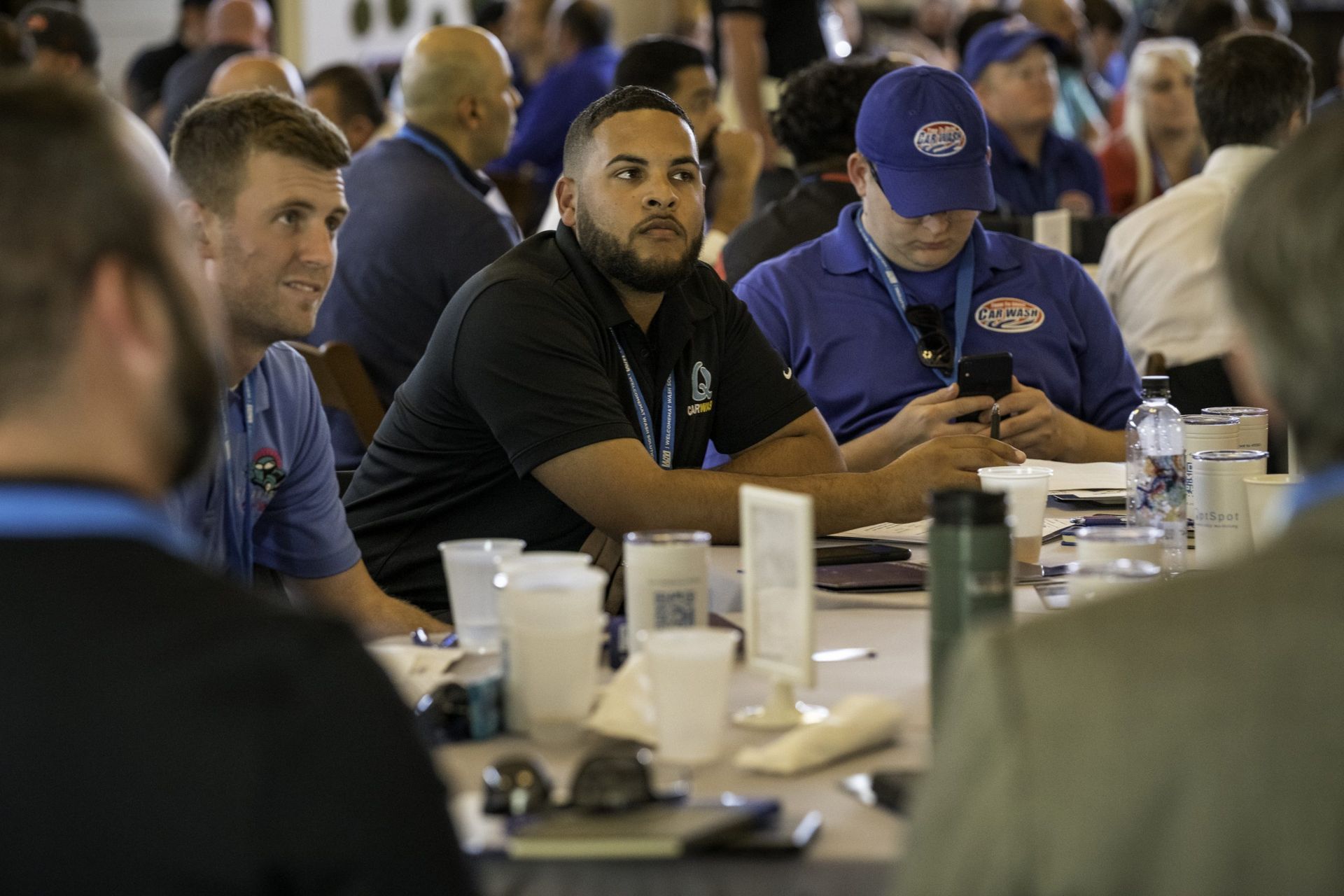 A group of men are sitting at a table looking at their phones.