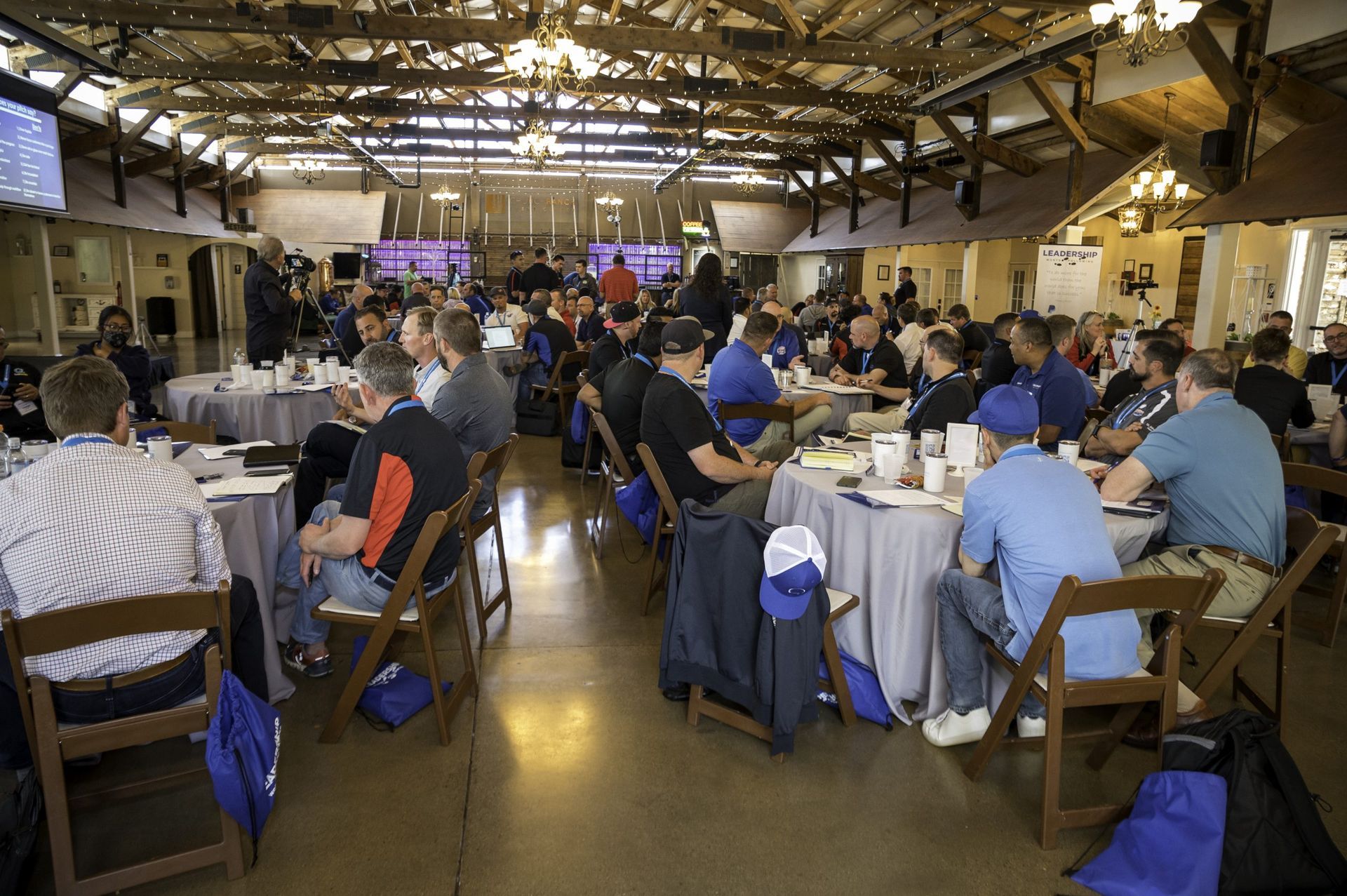 A large group of people are sitting at tables in a large room.