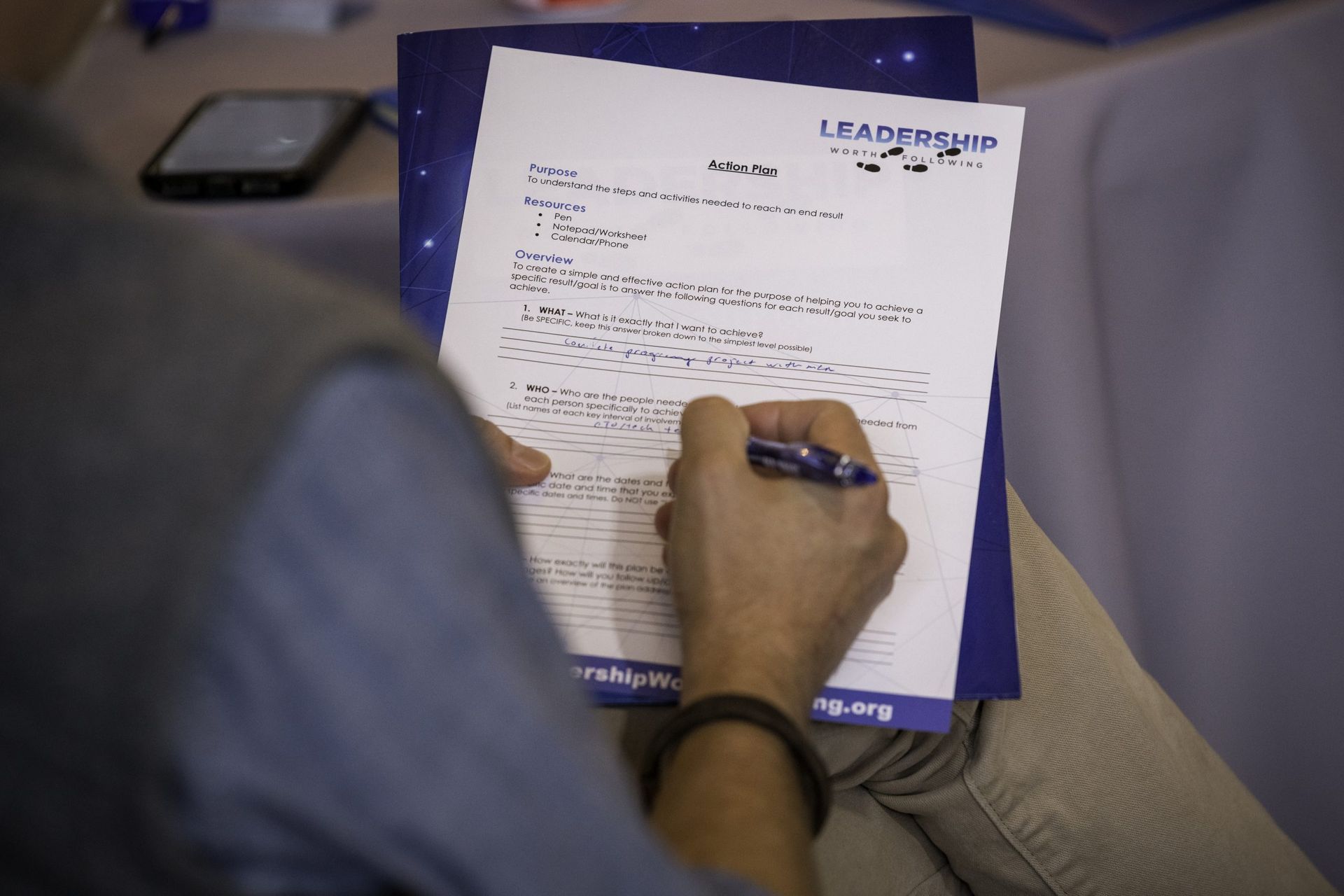 A person is writing on a piece of paper that says leadership