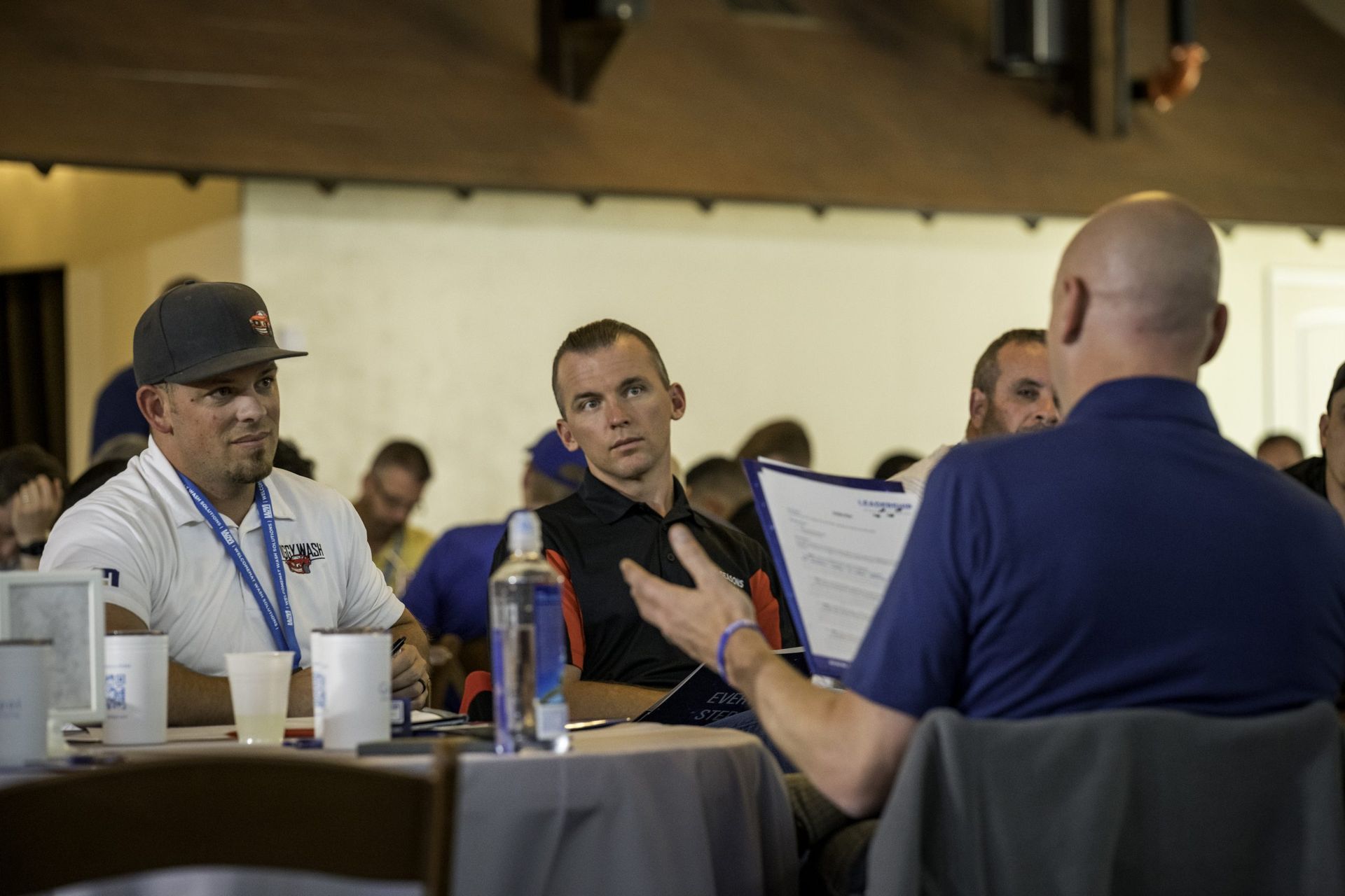 A group of men are sitting at tables talking to each other.