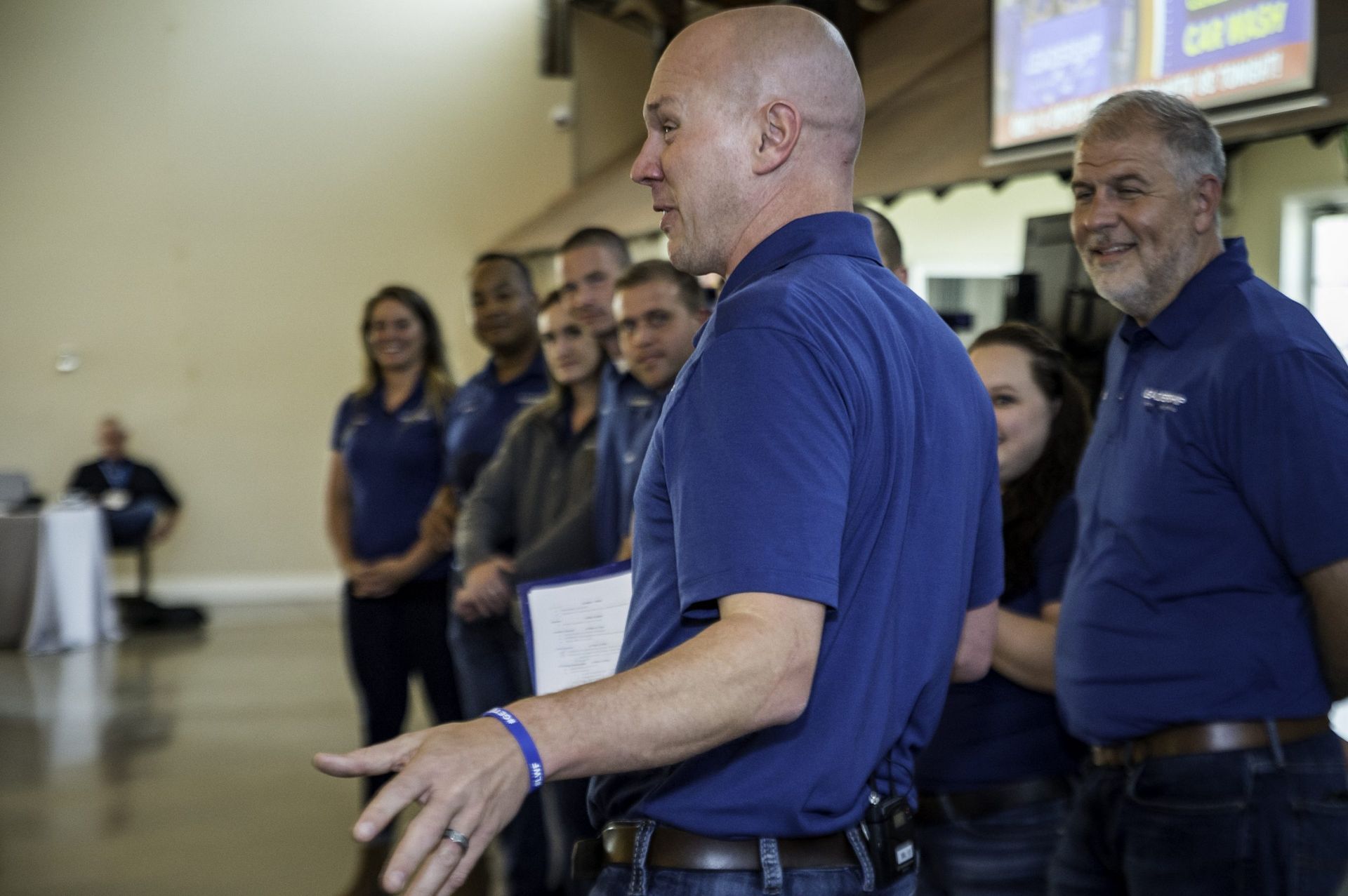 A man in a blue shirt is standing in front of a group of people.