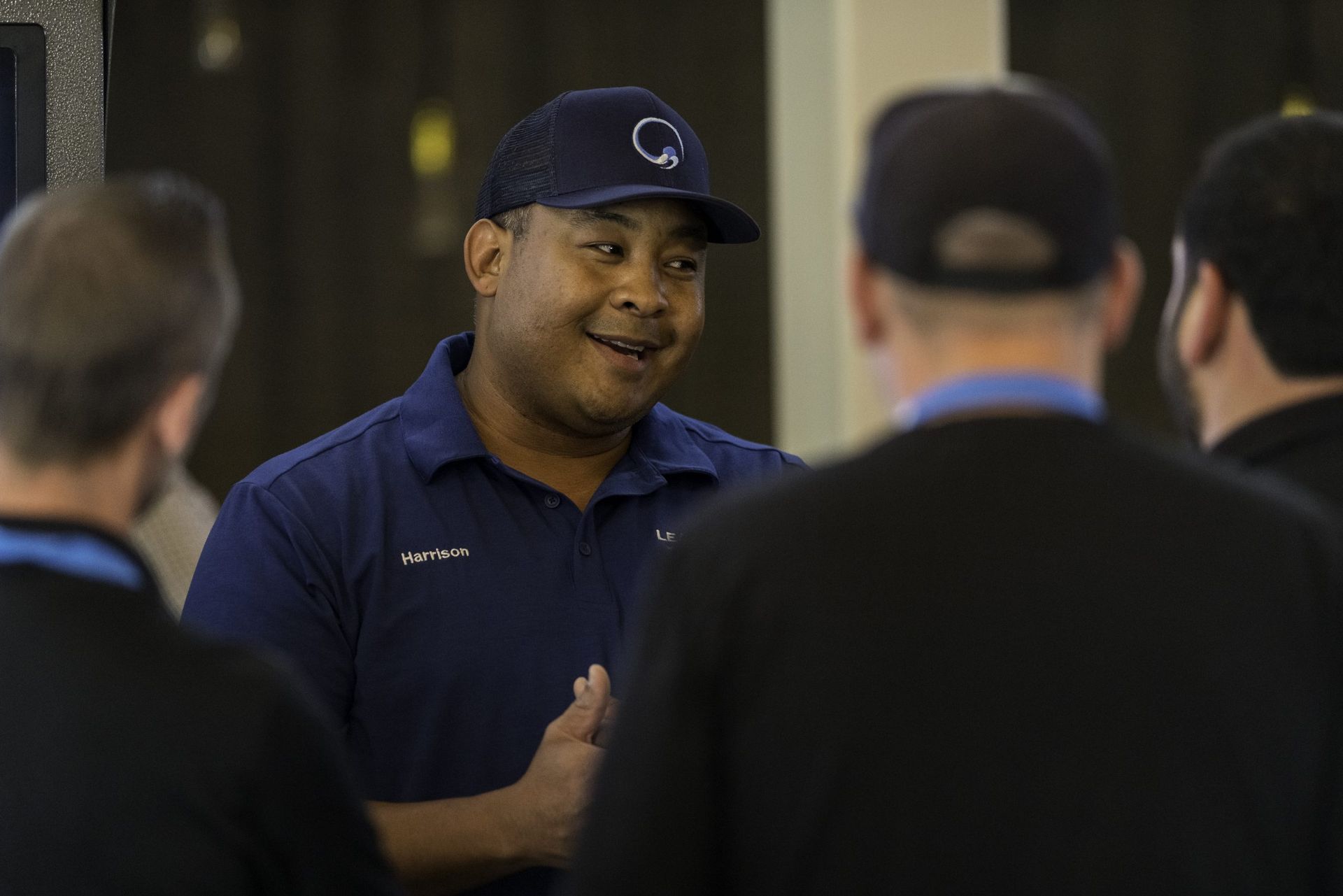 A man wearing a baseball cap is talking to a group of men.