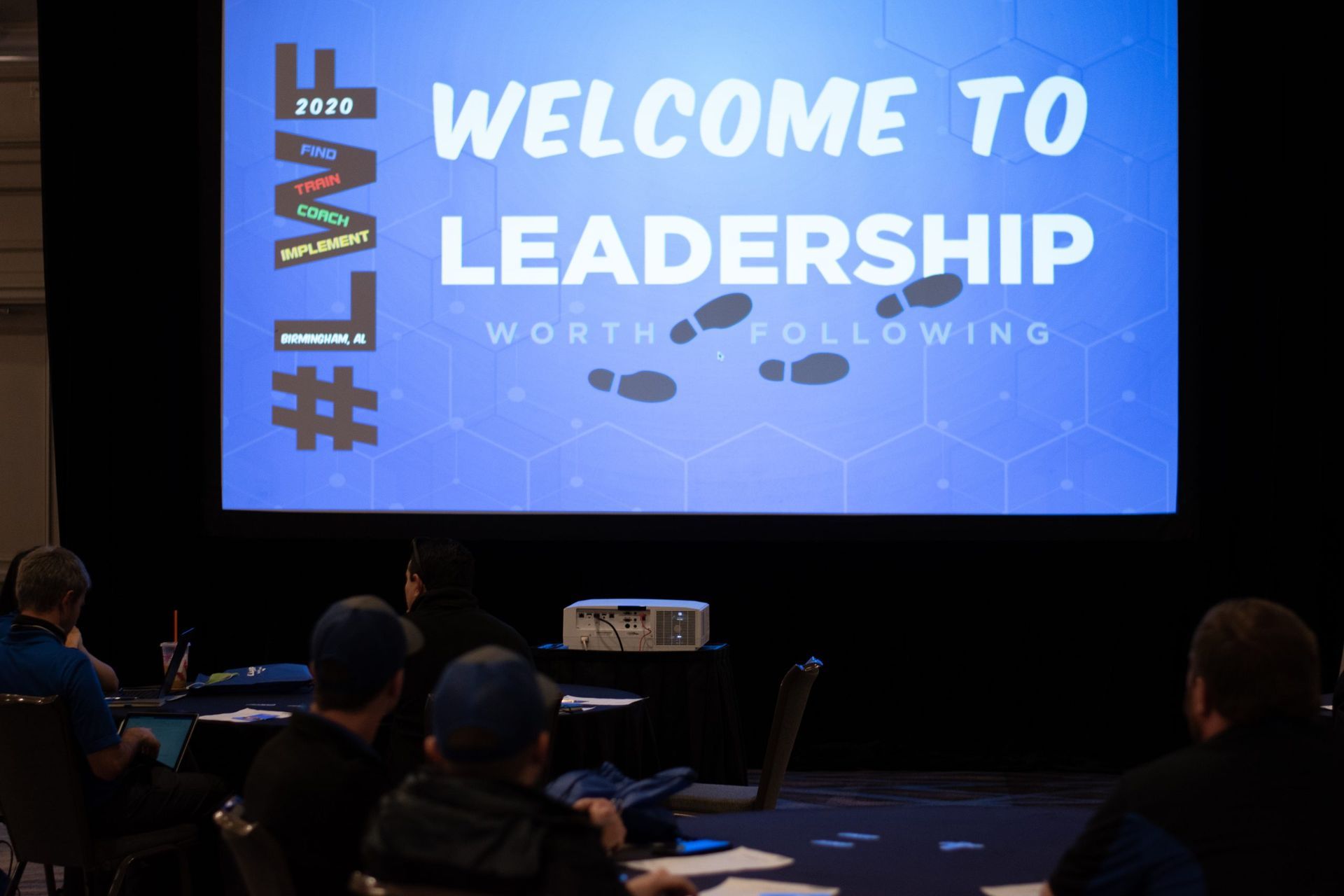People sitting in front of a screen that says welcome to Leadership Worth Following