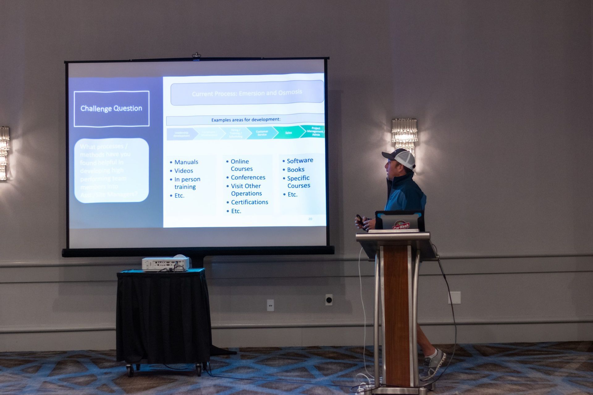 A man is giving a presentation in front of a large screen.