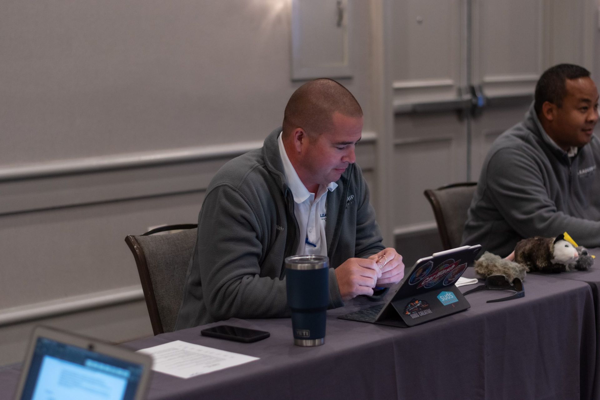 A man is sitting at a table using a tablet computer.