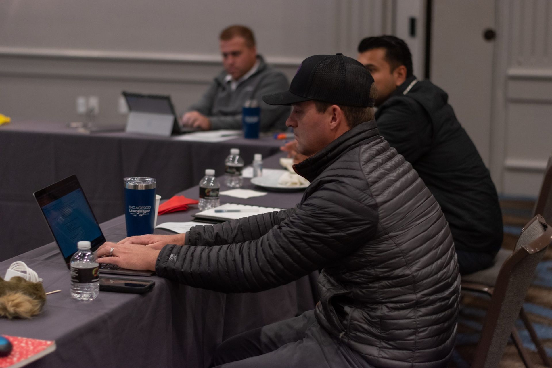 A man is sitting at a table using a laptop computer.