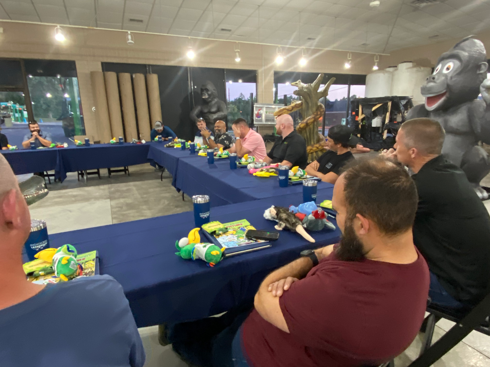 A group of men are sitting at long tables in a room.