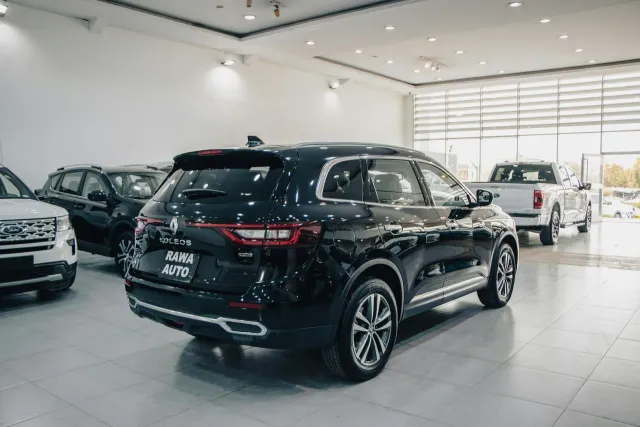 Black SUV displayed in a bright car showroom, with other vehicles nearby