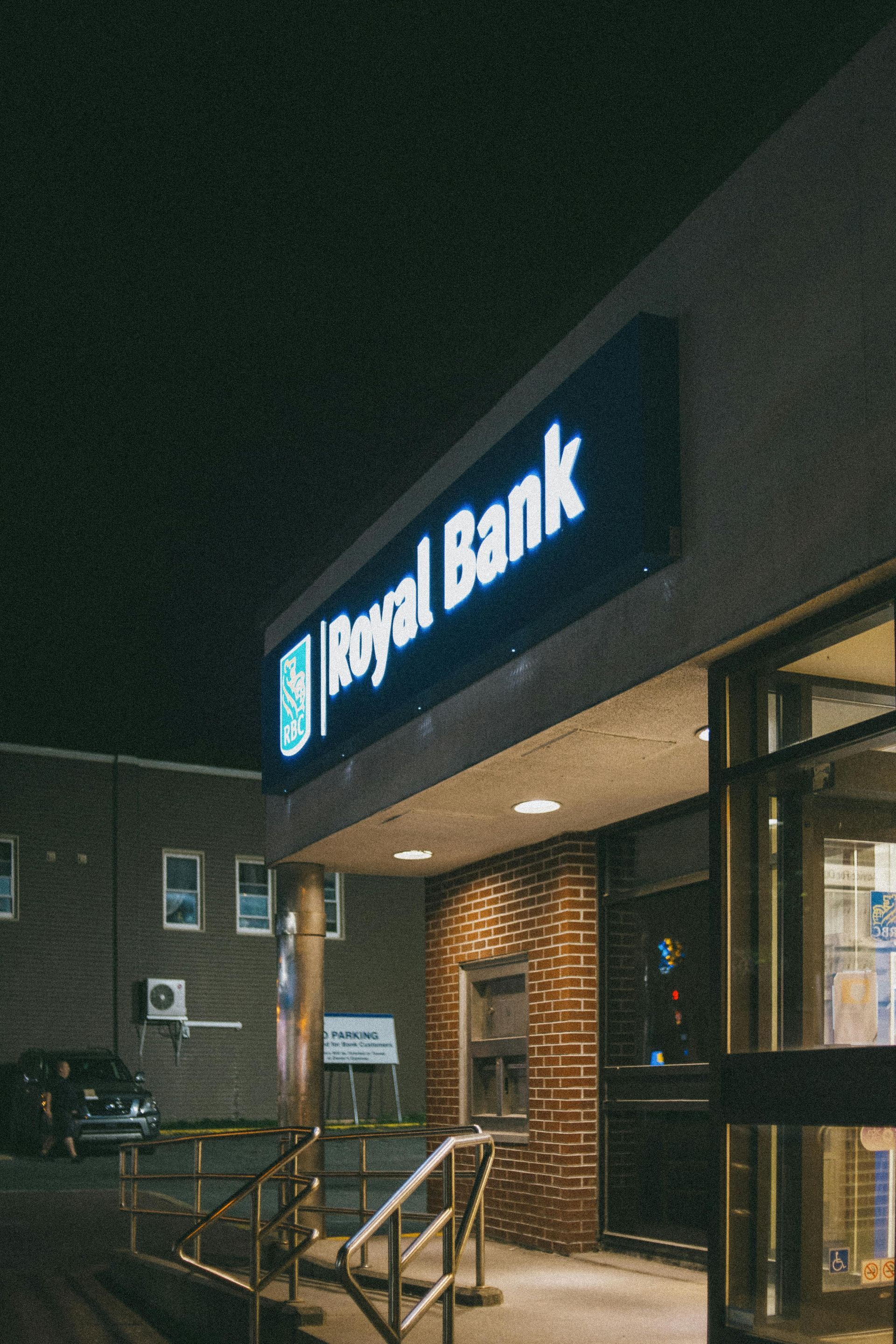 Illuminated bank entrance at night with glass doors and brick exterior