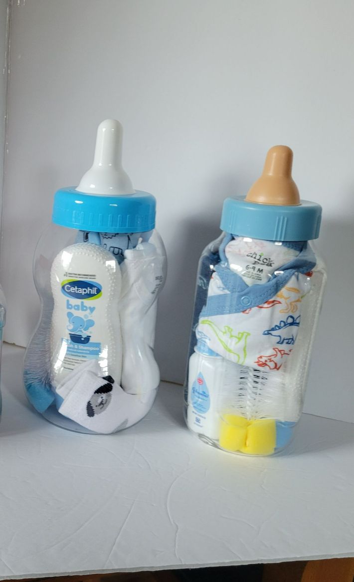 Two baby bottles with blue caps on a white surface, one clear with a white nipple, one decorated with animals.