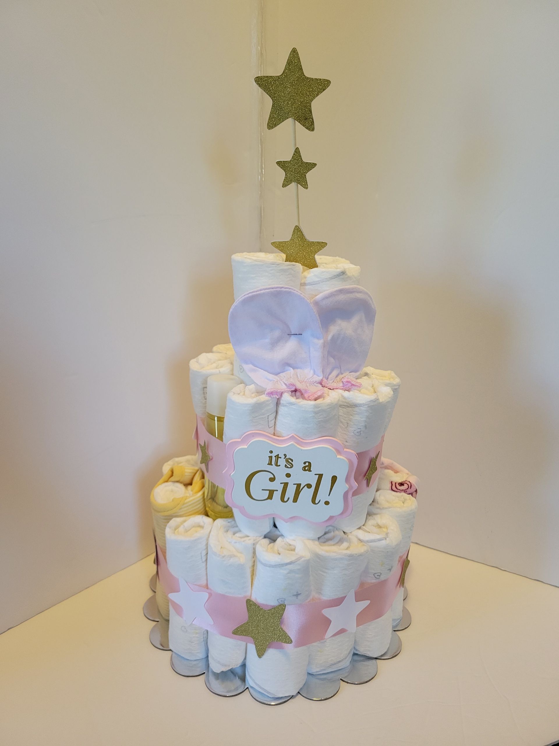 Pastel baby shower cake with star topper and “It’s a Girl!” plaque