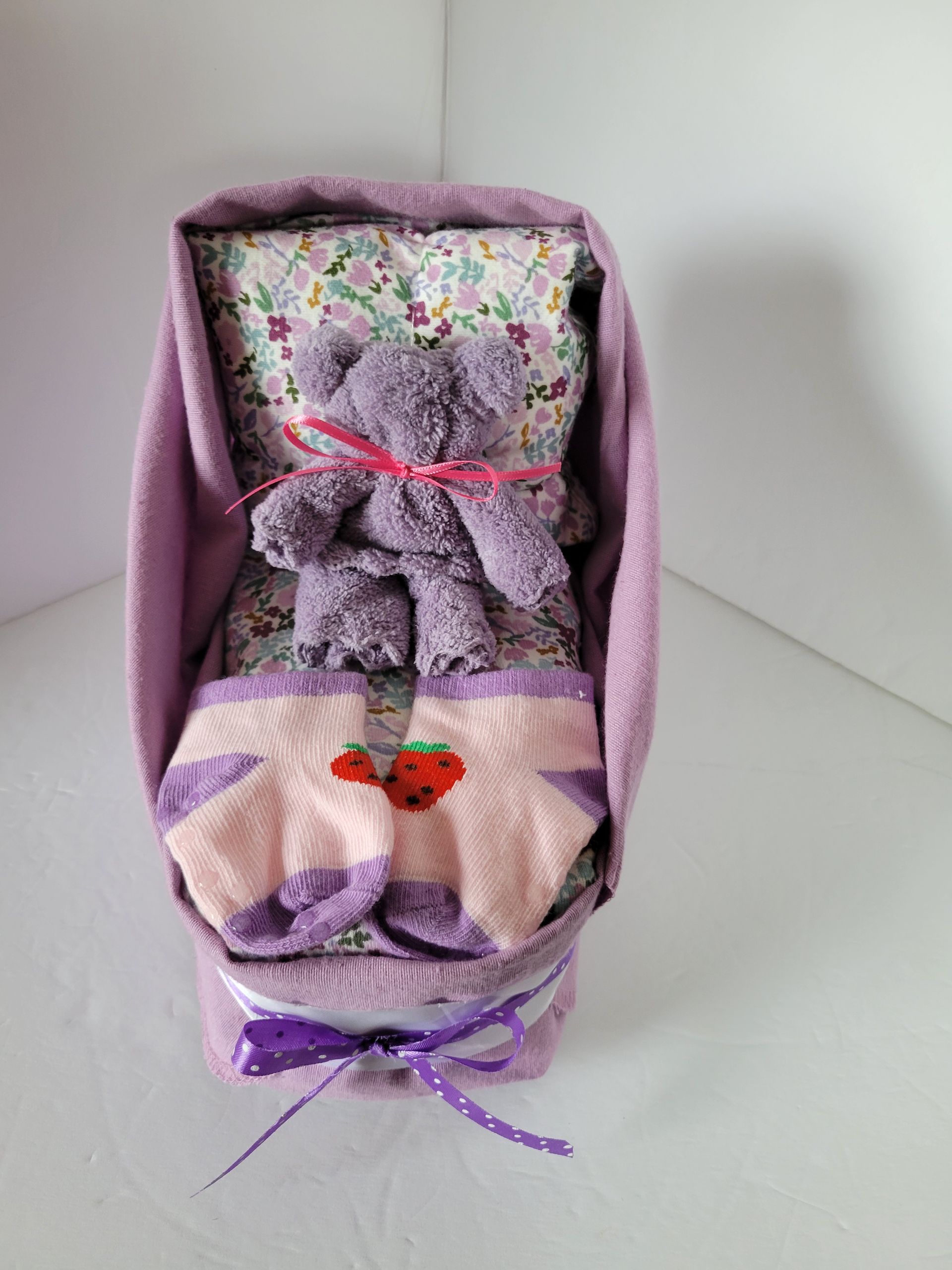 Purple fabric doll chair with floral cushion and ribbon bows on a white surface