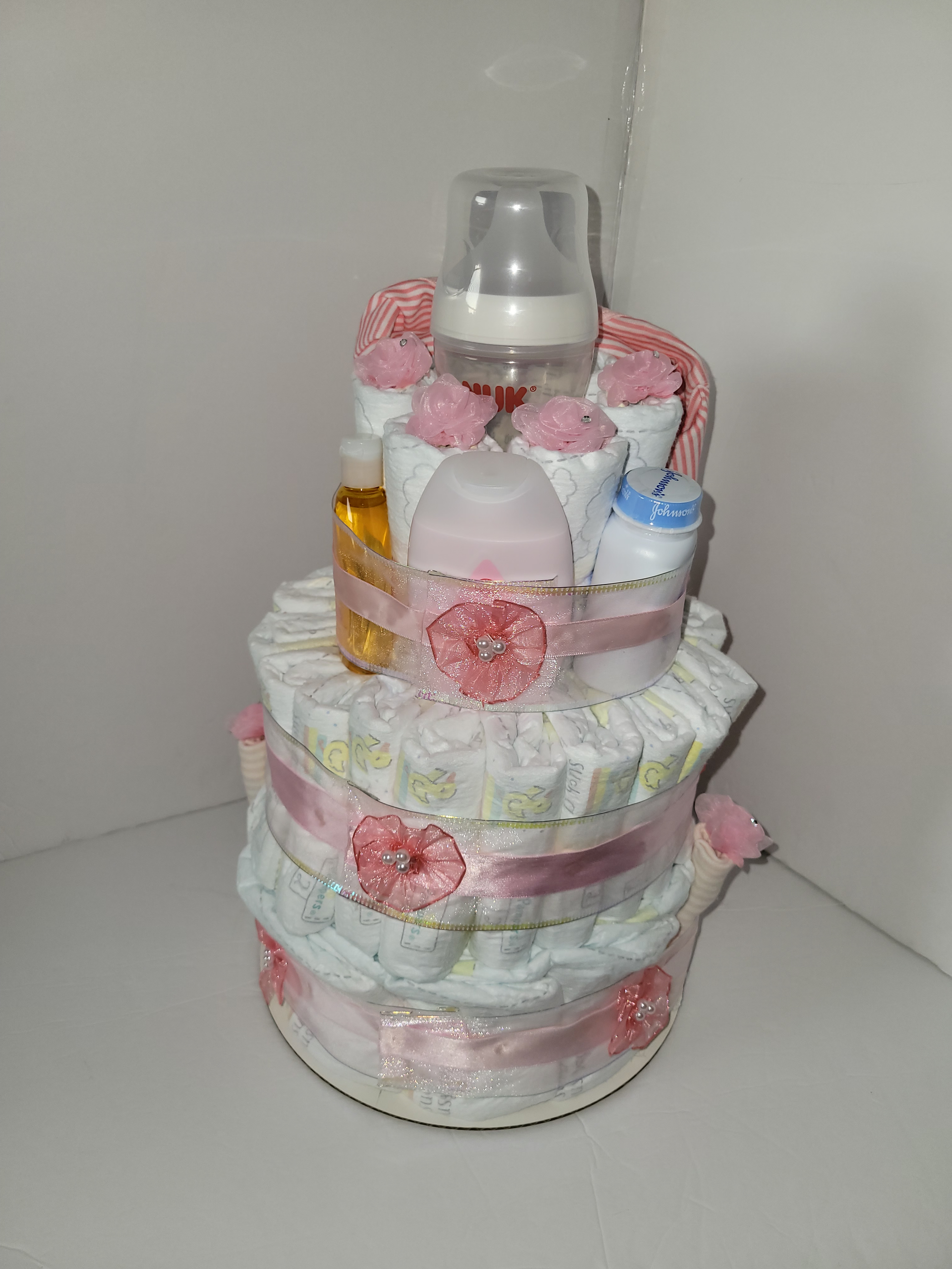 Pink and pastel diaper cake with a small teddy bear and name