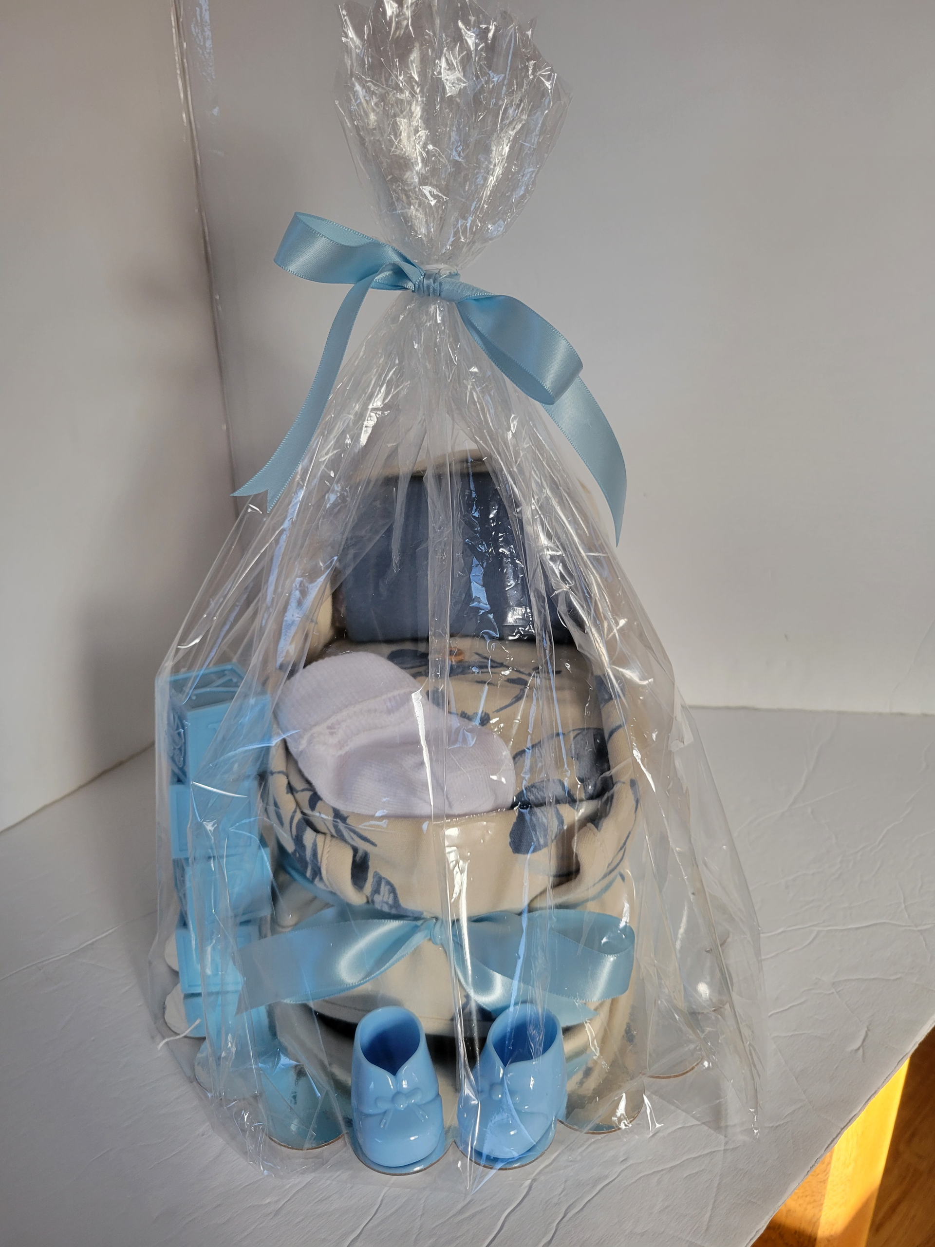 Blue and white doll wrapped in clear plastic, tied with a blue ribbon, sitting on a chair