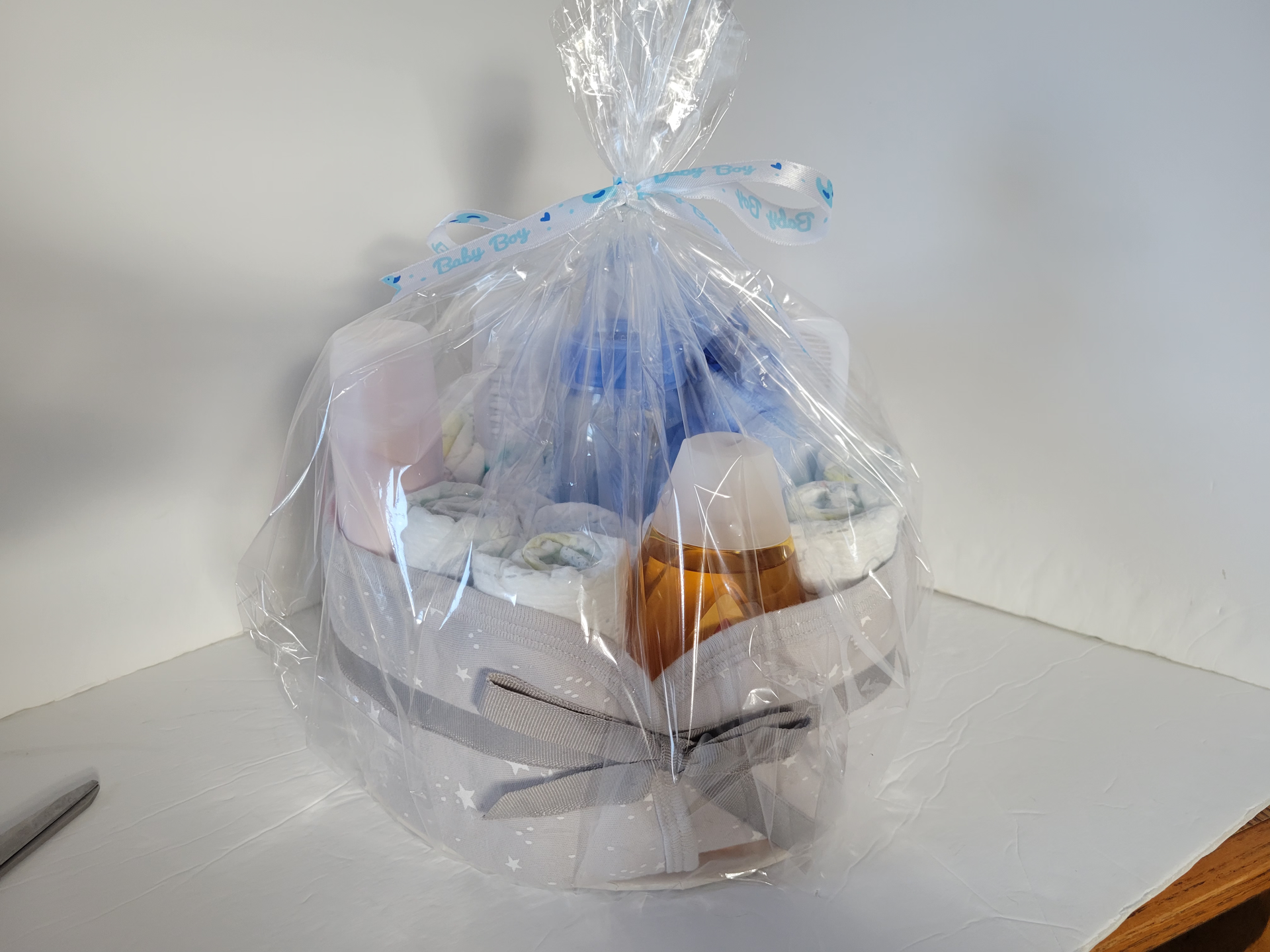 Wrapped gift basket with assorted items in a clear plastic bag on a table