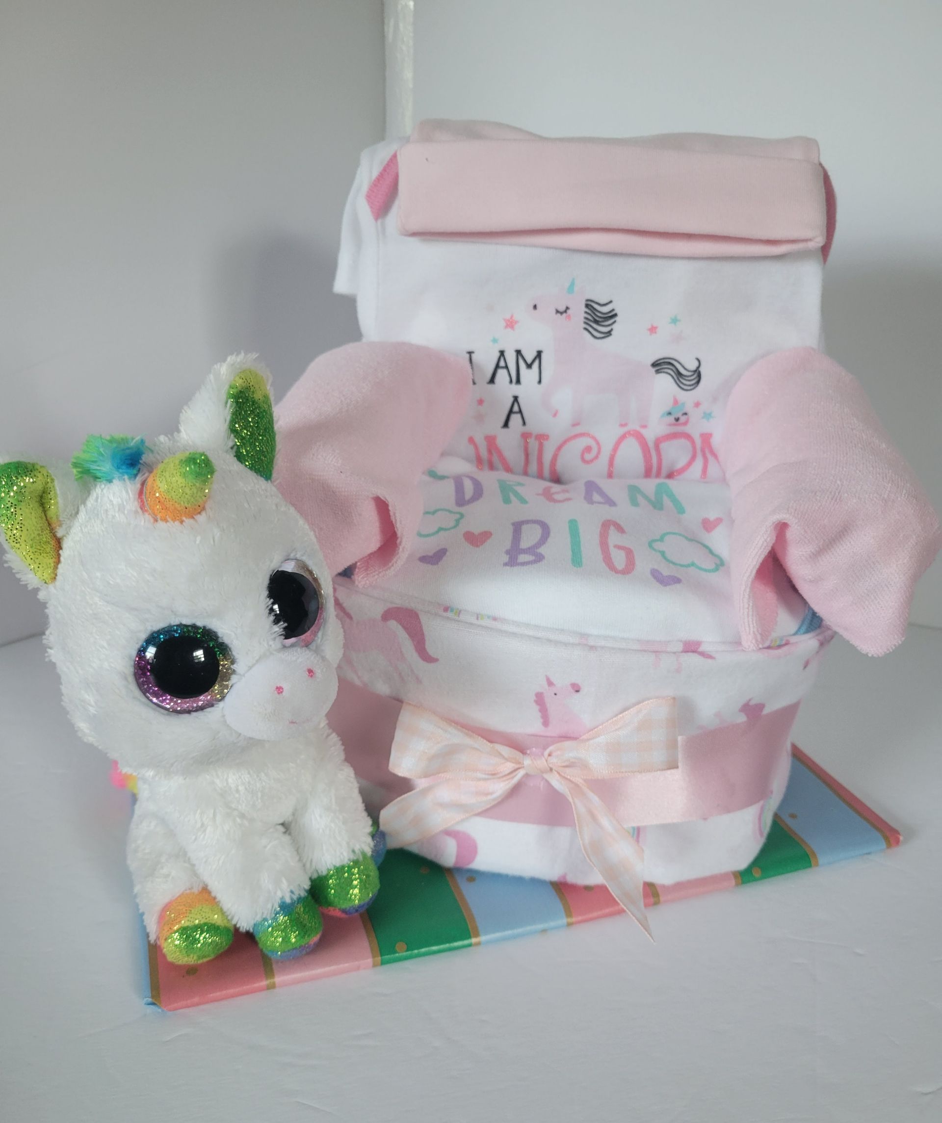 Pink-and-white handmade gift box with glittery unicorn figurine on a colorful base.