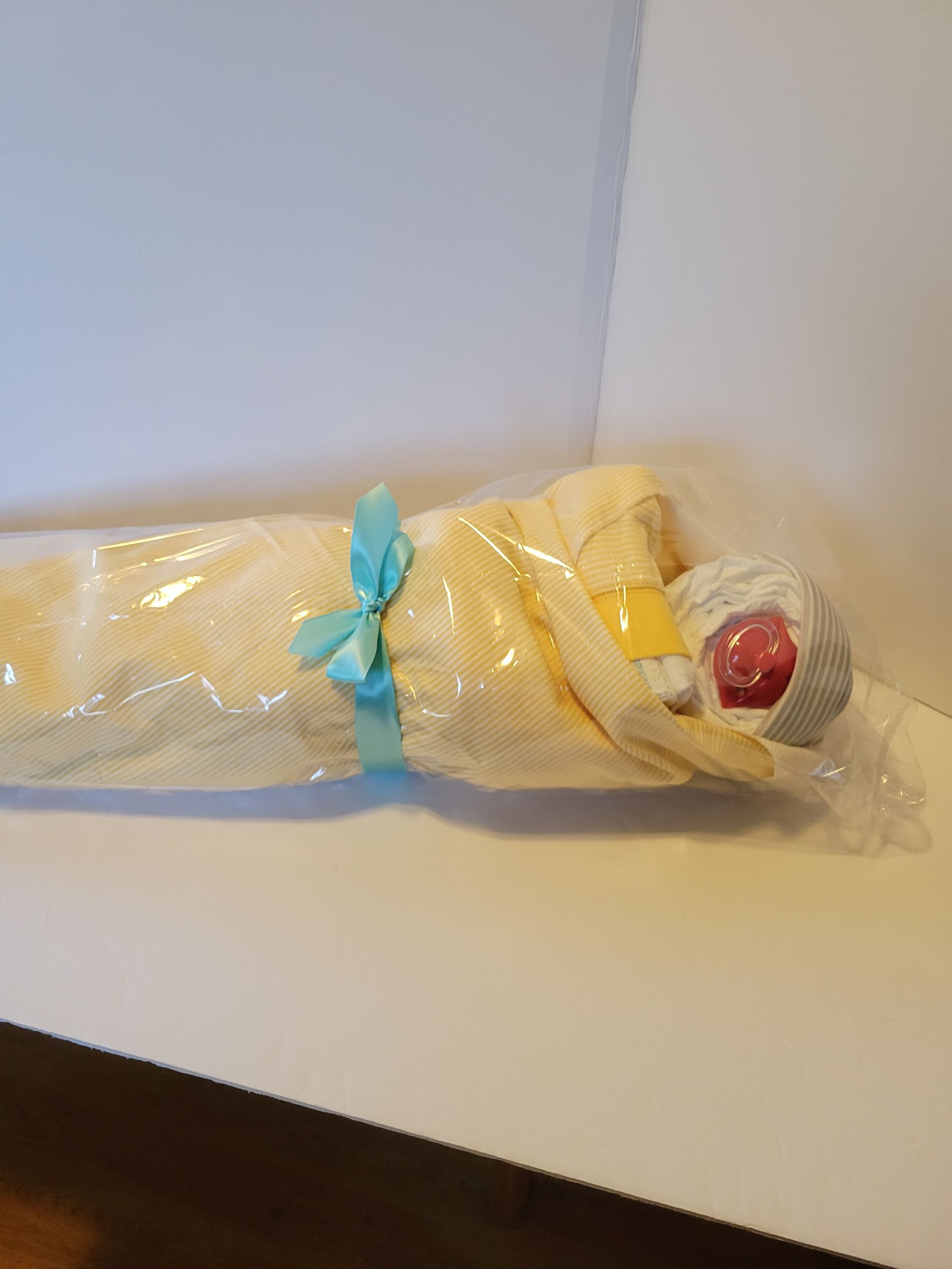 Wrapped doll or figurine in yellow fabric on a table, with a red face and hat visible.