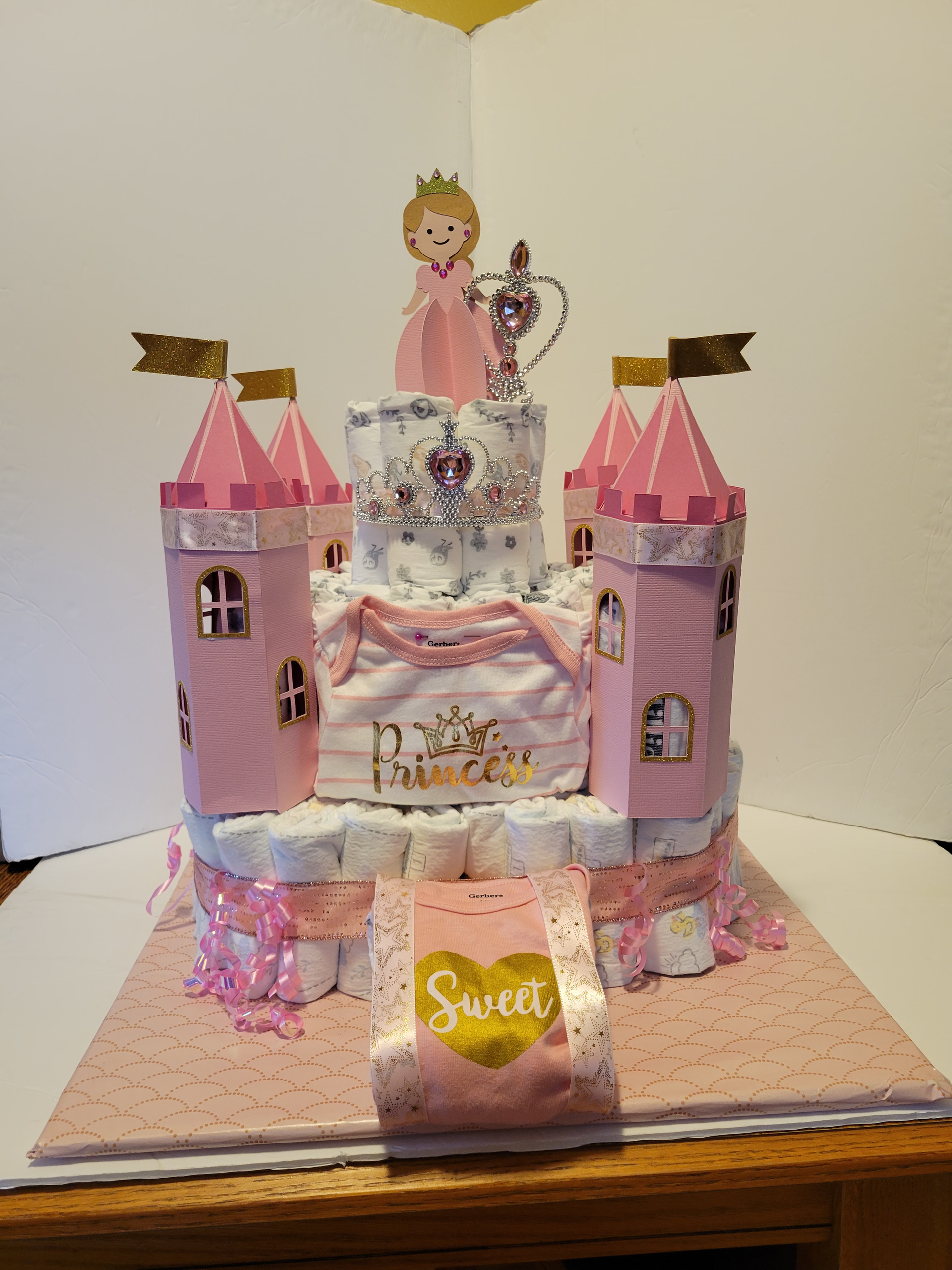 Pink castle-shaped cake with glittery decorations and a “Sweet” plaque on a tray