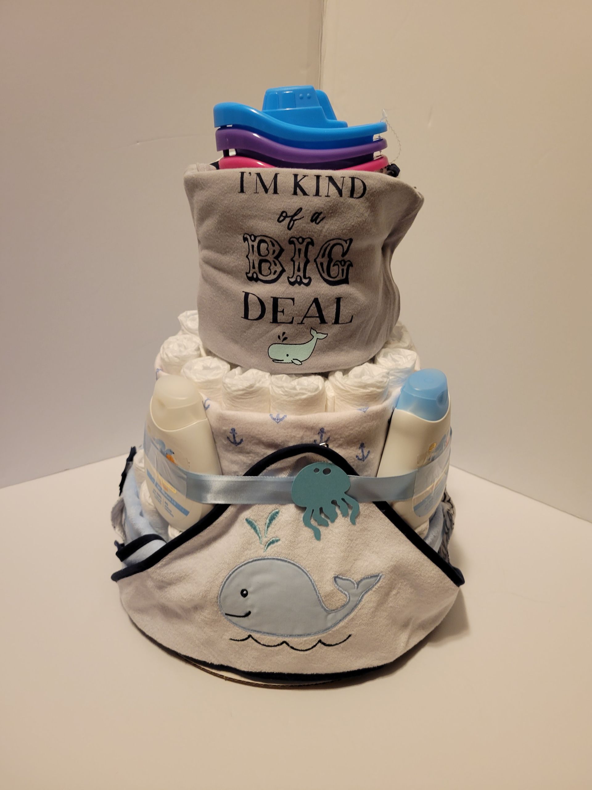 Two-tier diaper cake with gray “I’M KINDA A BIG DEAL” topper and blue whale decorations