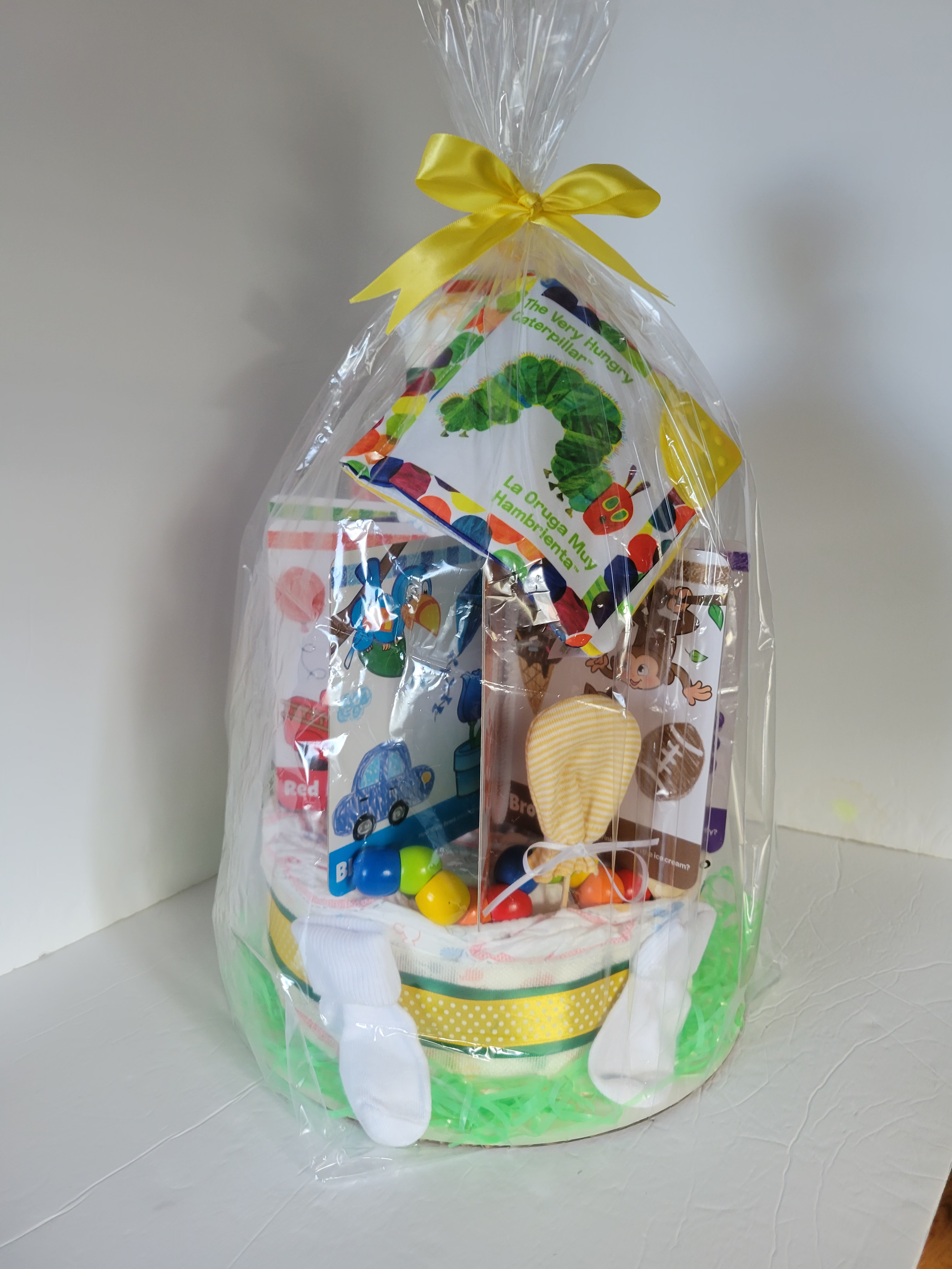 Clear gift basket with colorful candy, cookies, and snacks, wrapped in cellophane with a yellow bow.