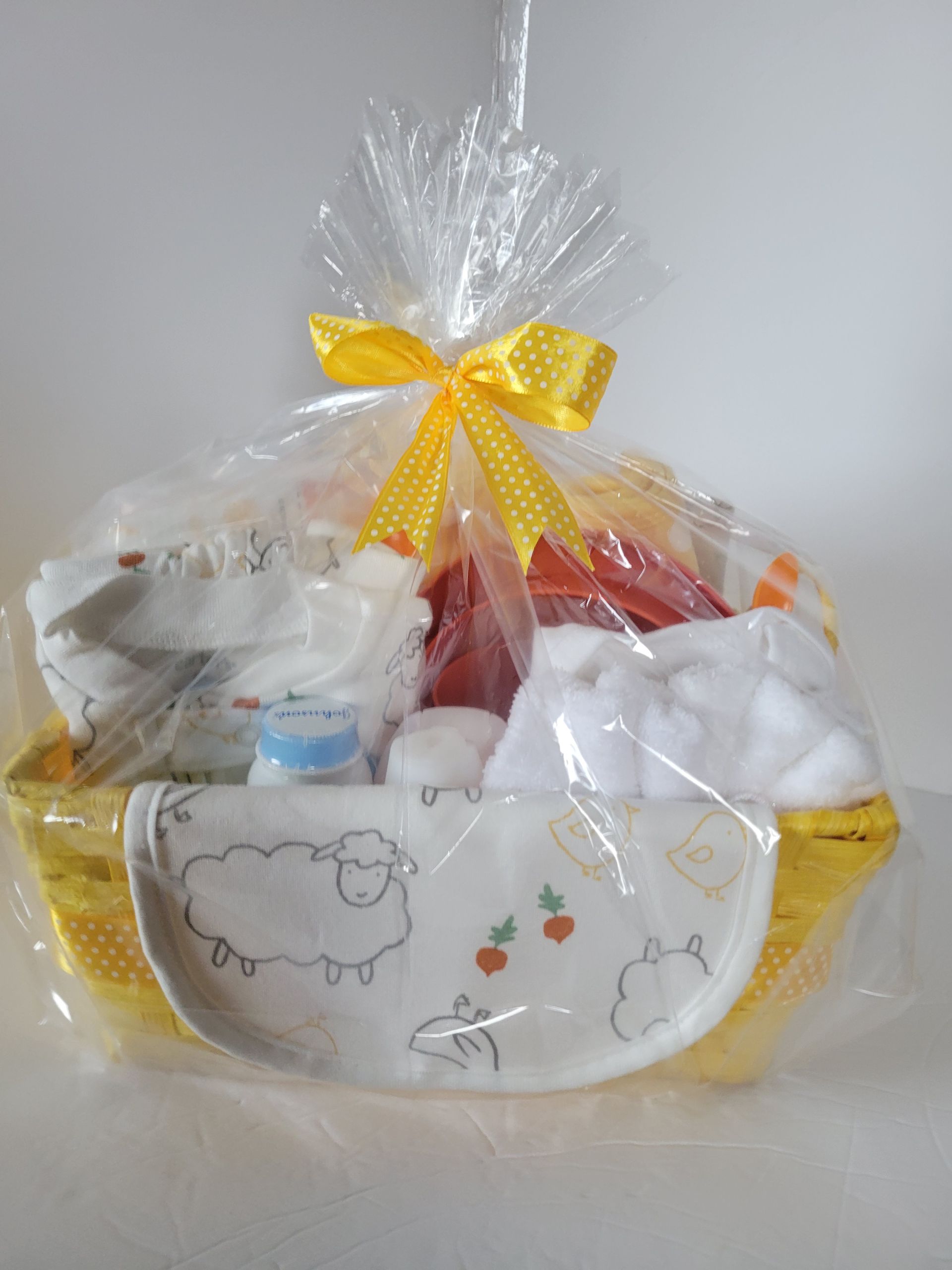 Gift basket with wrapped treats and a yellow bow in a clear cellophane bag