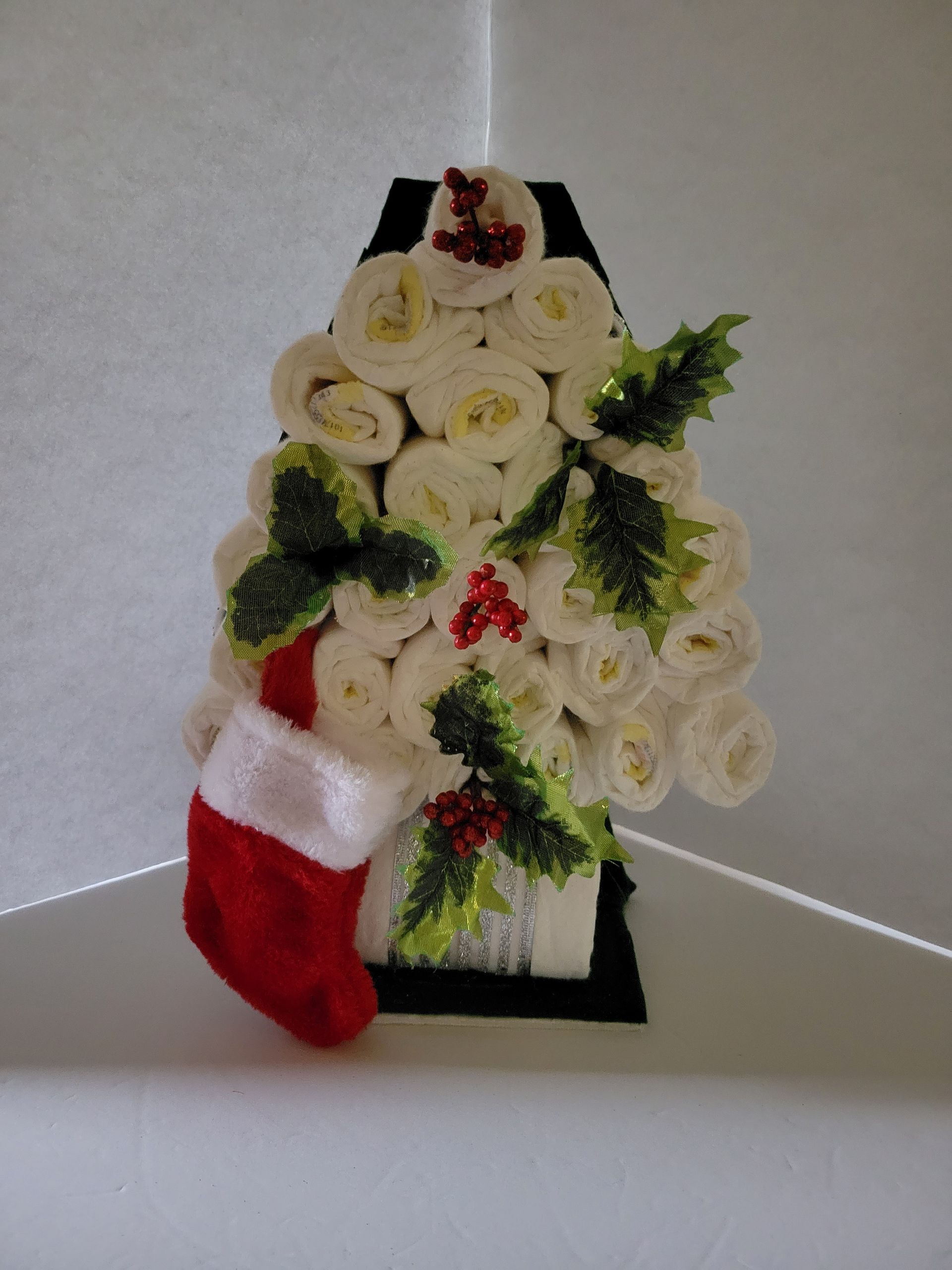 Christmas stocking made of rolled white flowers with red and green holiday accents on a black stand