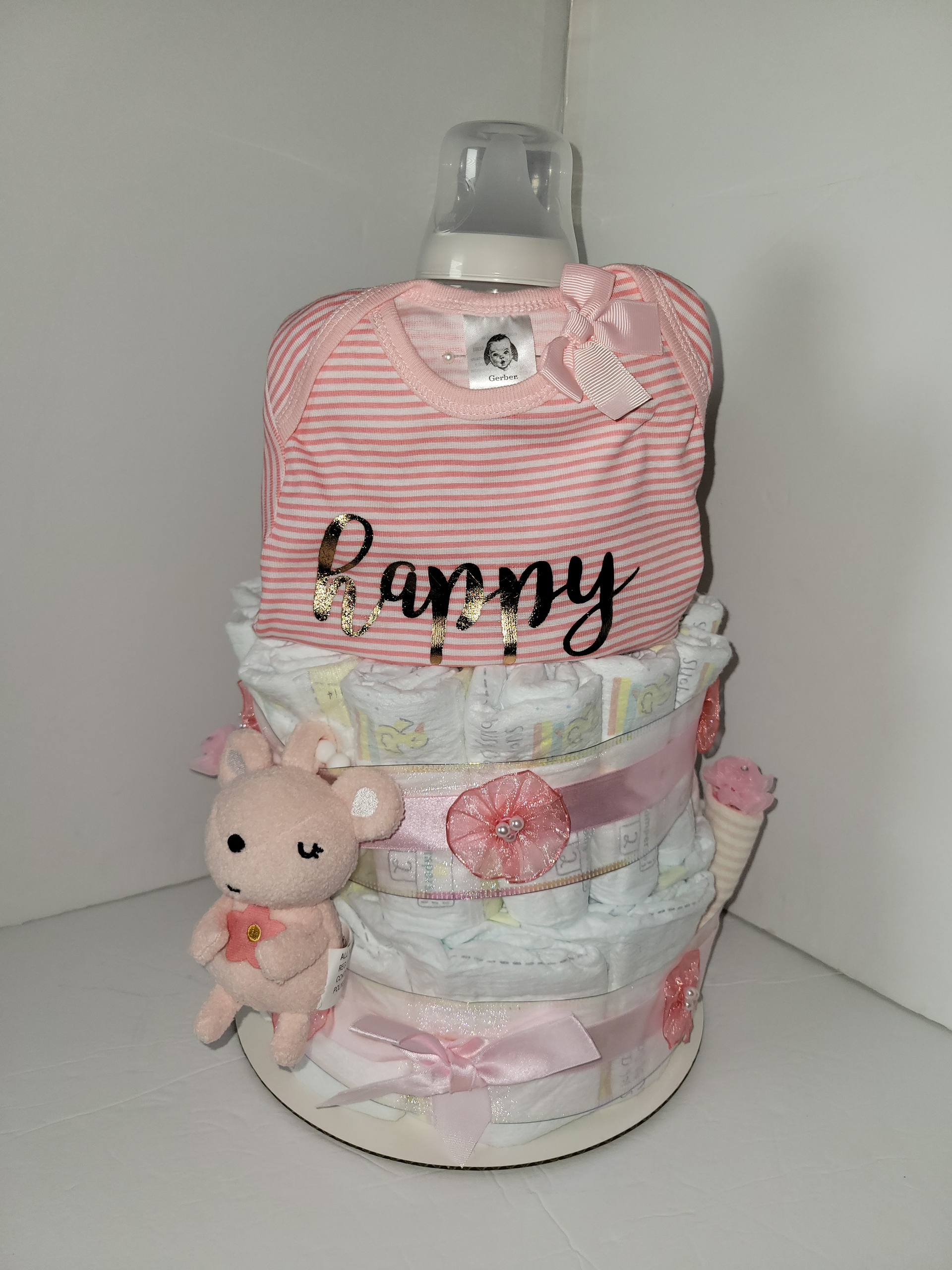 Pink and pastel diaper cake with a small teddy bear and name