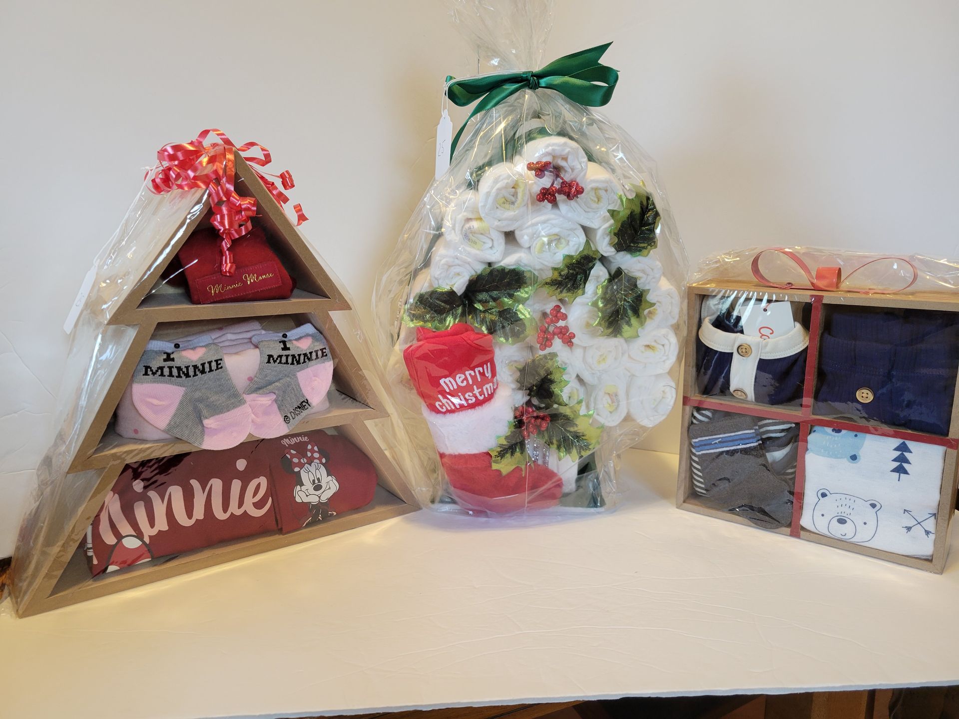 Three small gift boxes wrapped in clear cellophane, arranged on a white surface.