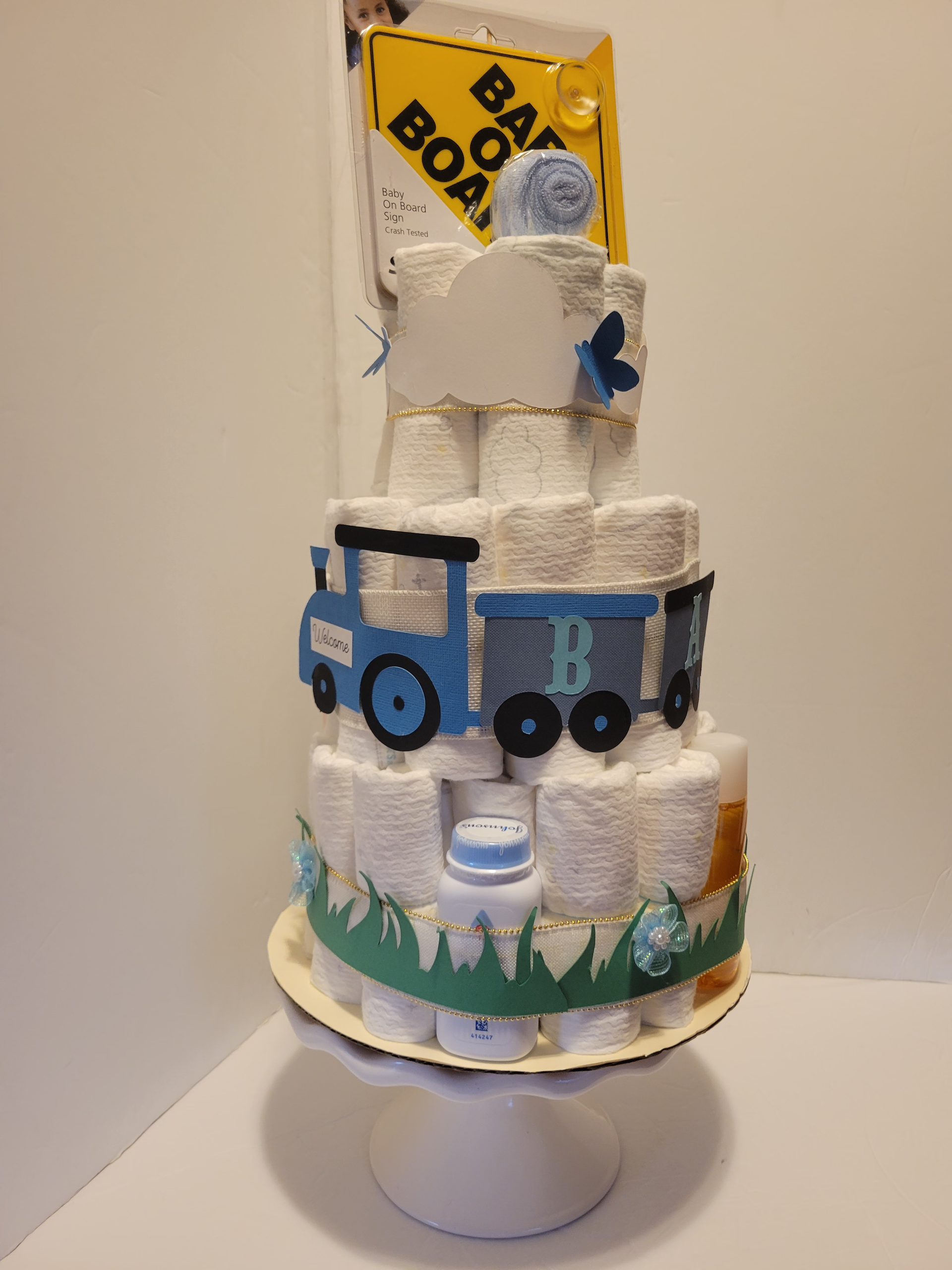 Snowman-themed cake with a blue truck and yellow box topper on a white stand