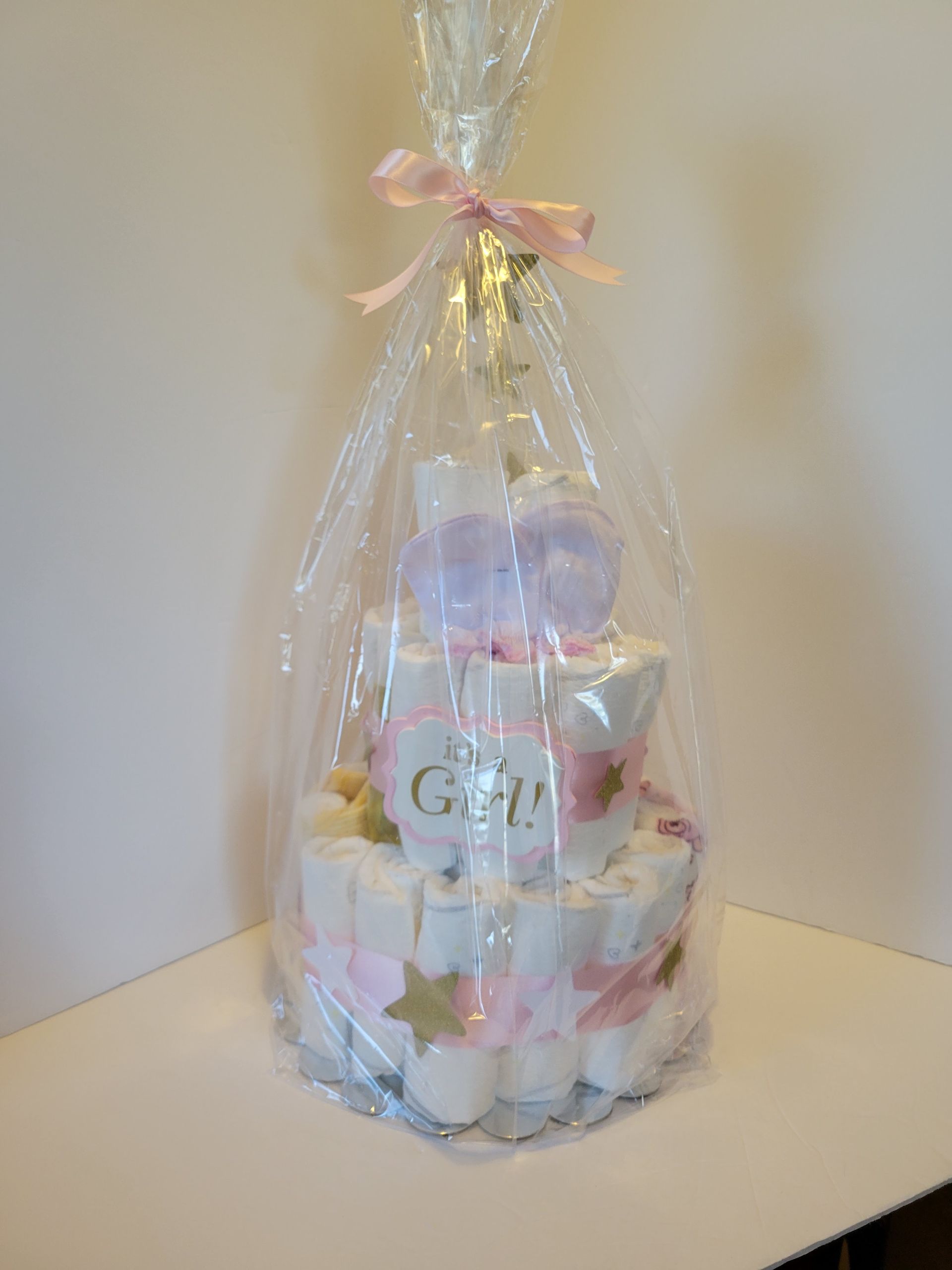 Pastel baby shower cake with star topper and “It’s a Girl!” plaque