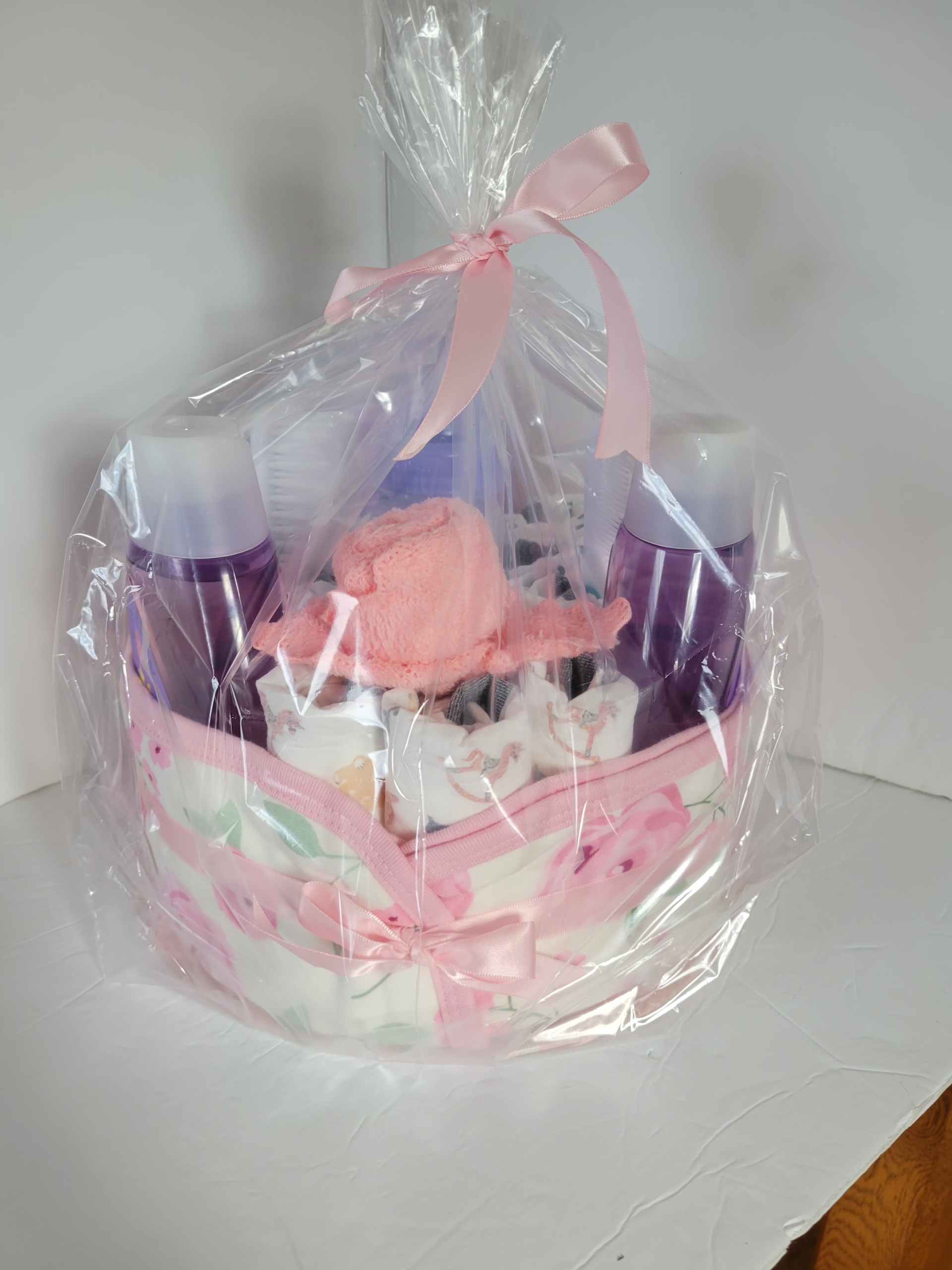 Wrapped pink gift basket with purple and white items, tied with a sheer ribbon