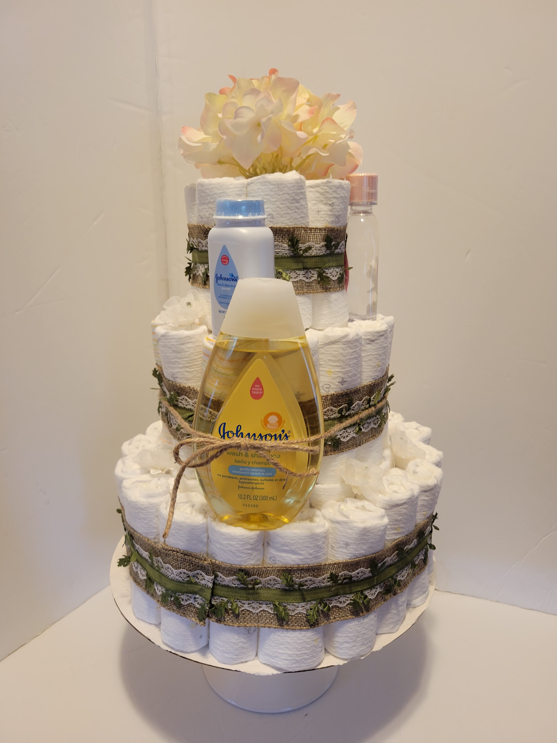 Two-tier white floral centerpiece with peach and pink flowers on a stand, plus small flowers in a vase nearby