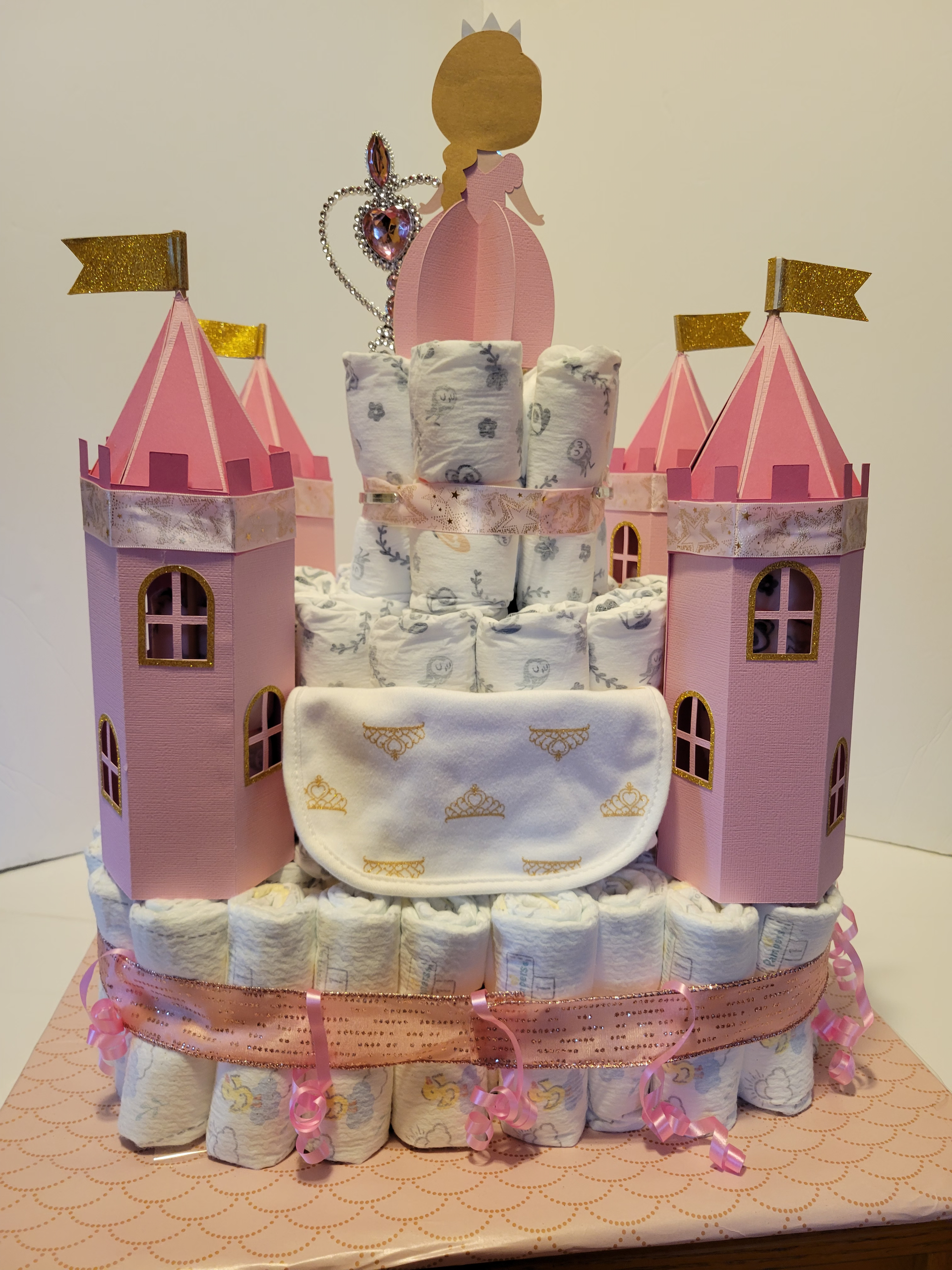 Pink castle-shaped cake with towers, flags, and white frosting decorations
