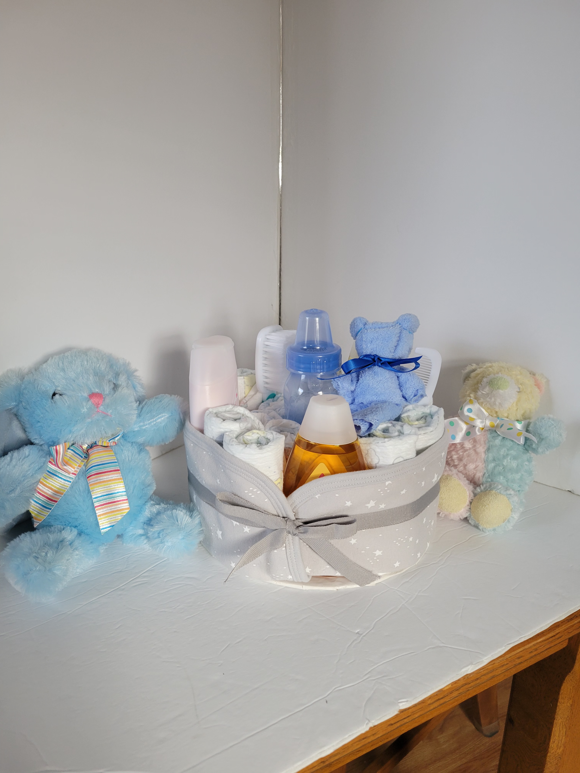Teddy bears and baby items arranged in a white basket on a shelf