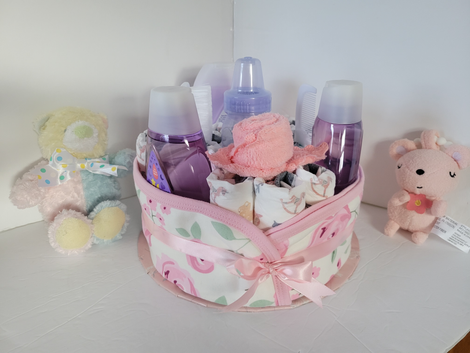 Pink gift basket with toiletries, wrapped in ribbon, flanked by two stuffed animals on a white shelf