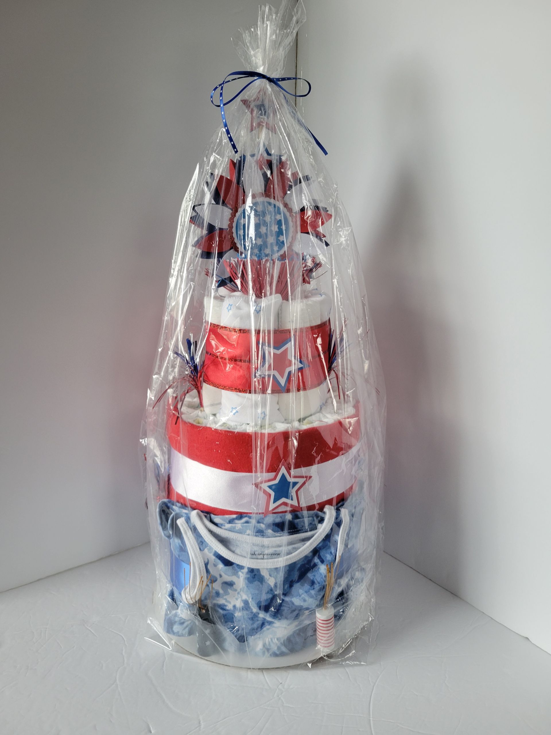 Red, white, and blue decorated tiered cake with a star topper on a plain background